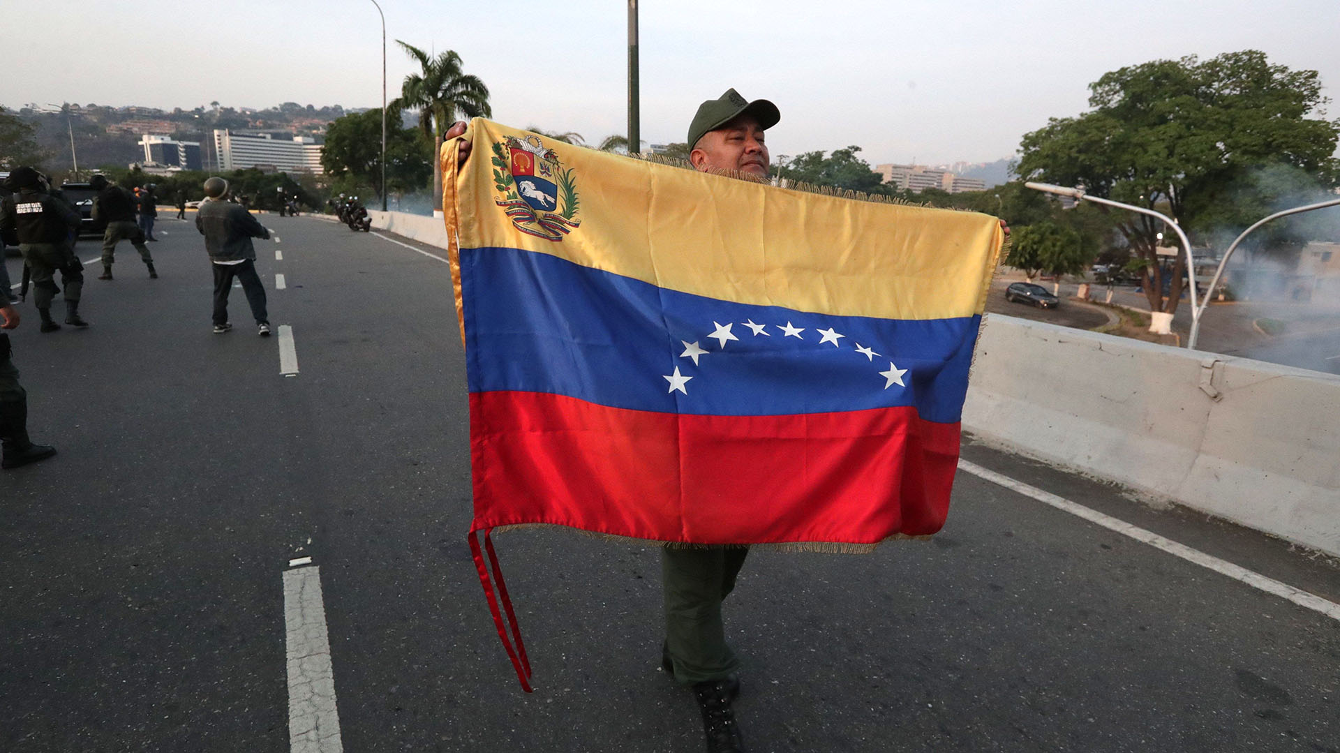 Un militar despliega una bandera en la base de La Carlota, al este de Caracas, donde ha sido conducido el opositor Leopoldo López, tras ser liberado este martes y donde se ha reunido con el presidente Juan Guaidó, que ha anunciado que los militares han dado el paso para unirse a él. EFE/Rayner Peña