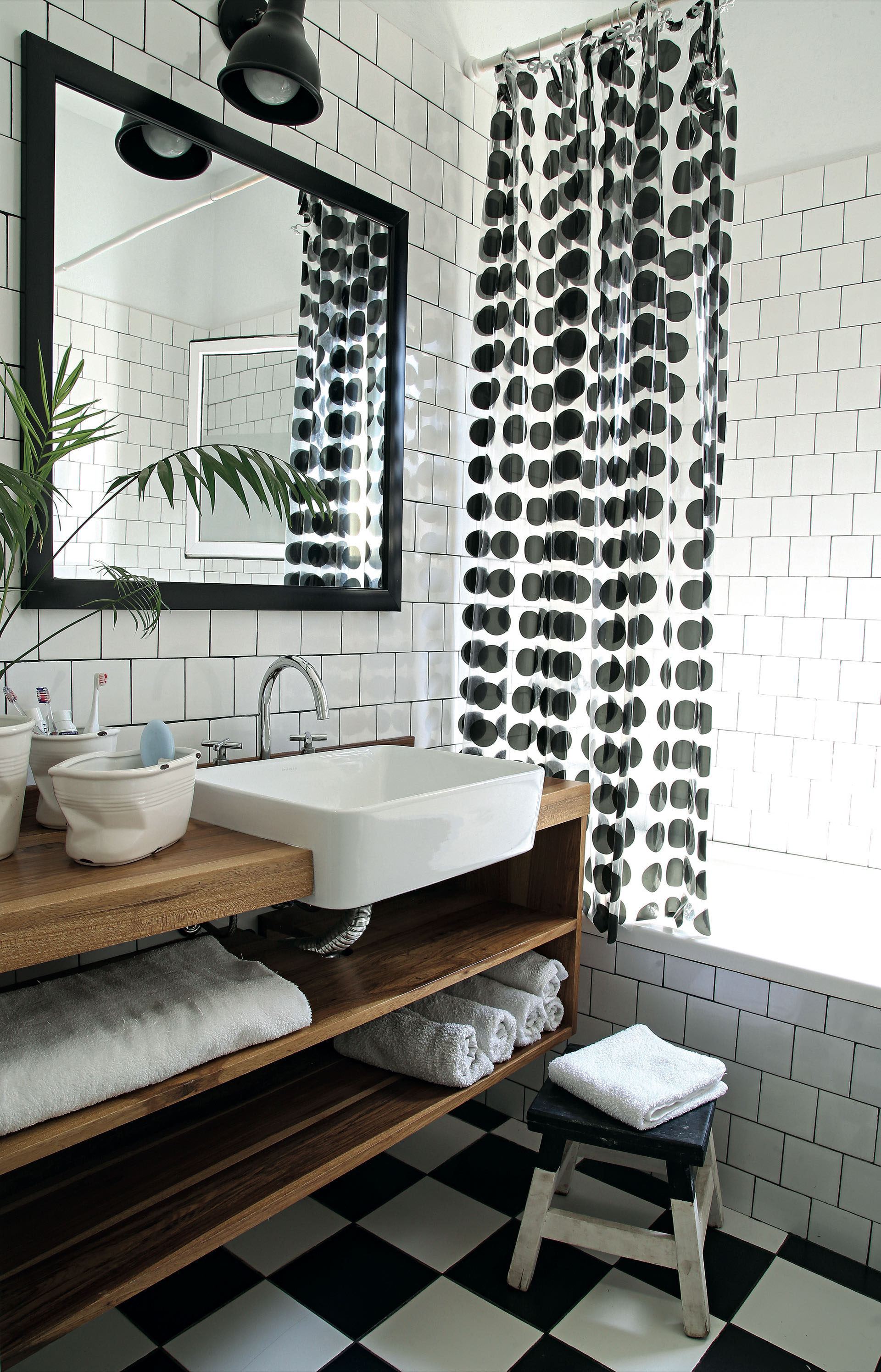 Monocromo absoluto para el baño. El blanco y negro del piso de damero se replica en los azulejos con junta a contratono y en la cortina.