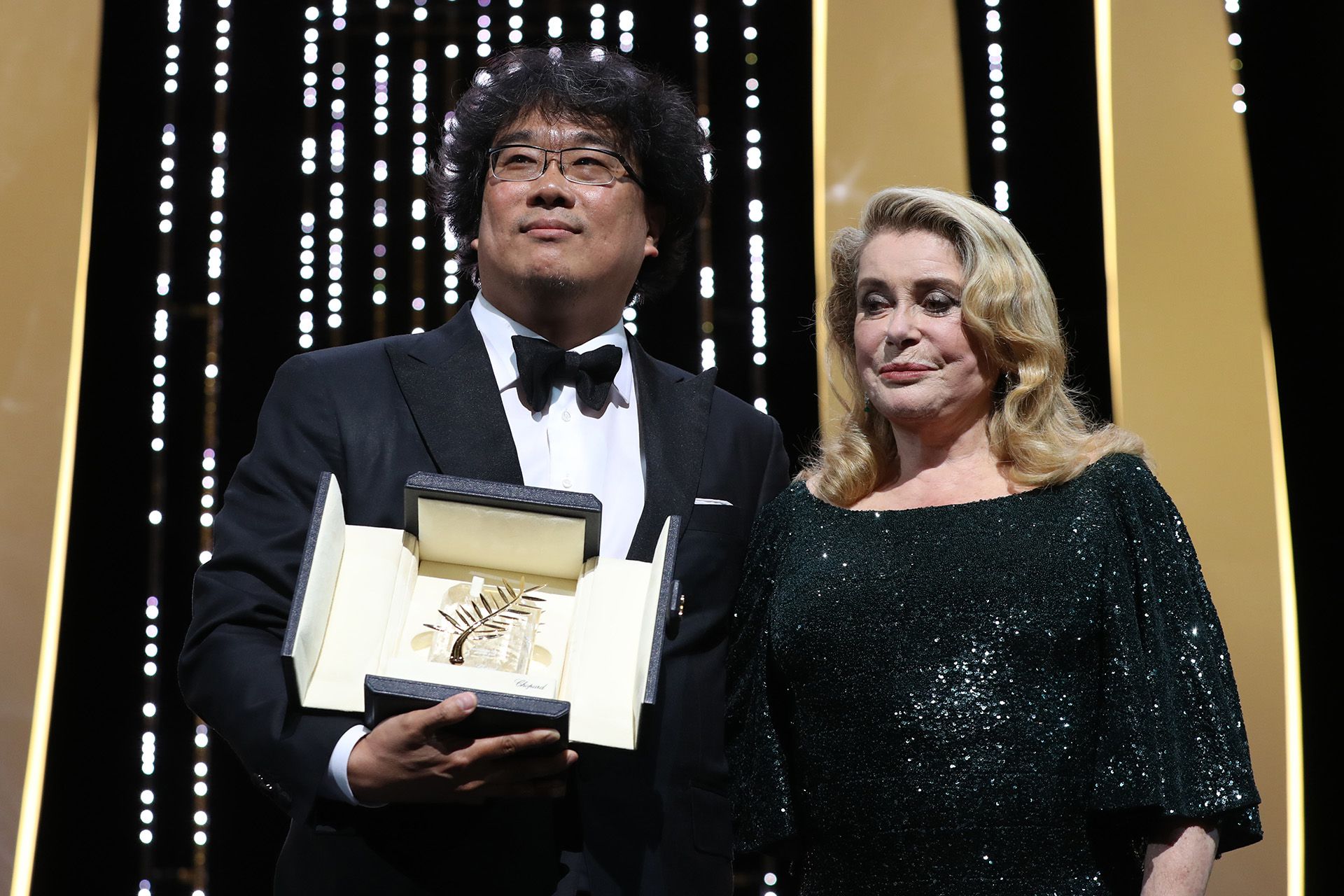 Bong Joon-Ho junto a Catherine Deneuve al recibir la Palma de Oro por “Parasite” en Cannes (Photo by Valery HACHE / AFP)