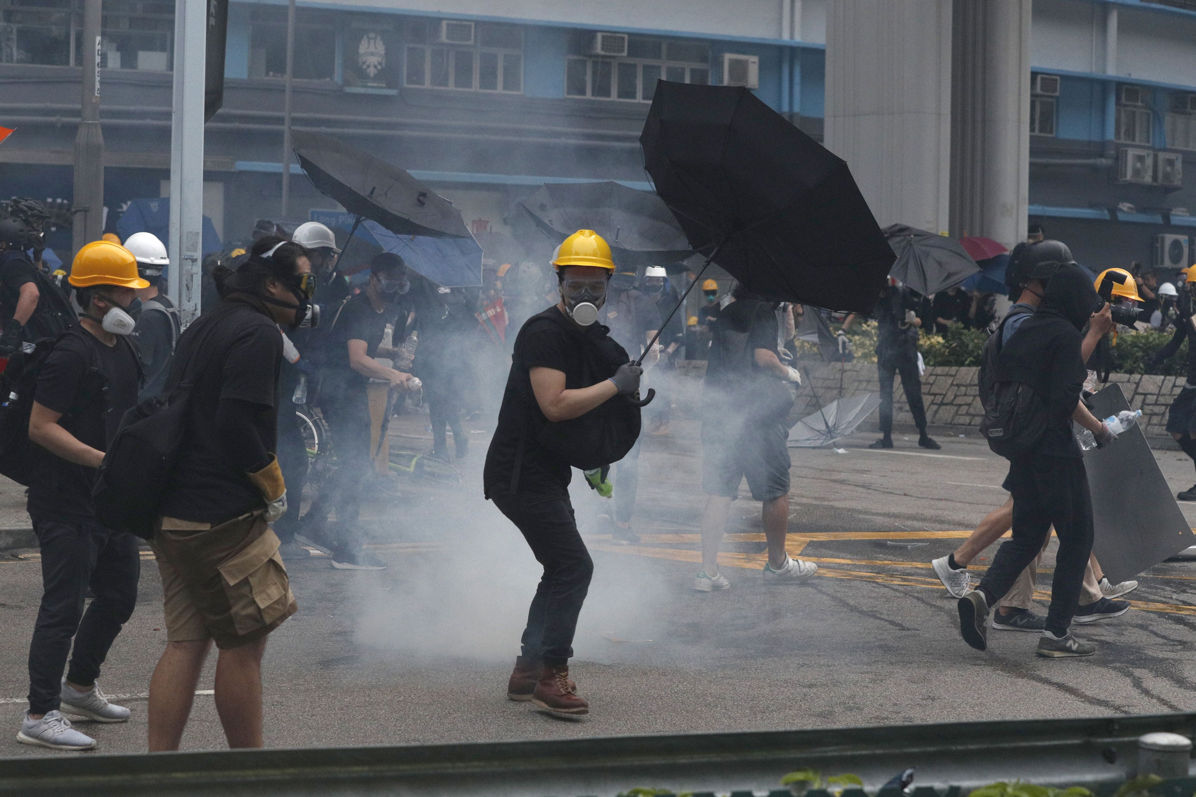 Manifestantes devuelven granadas de gas lacrimógeno lanzadas por la policía durante un enfrentamiento en el distrito de Yuen Long, Hong Kong, sábado 27 de julio de 2019. (AP Foto/Bobby Yip)