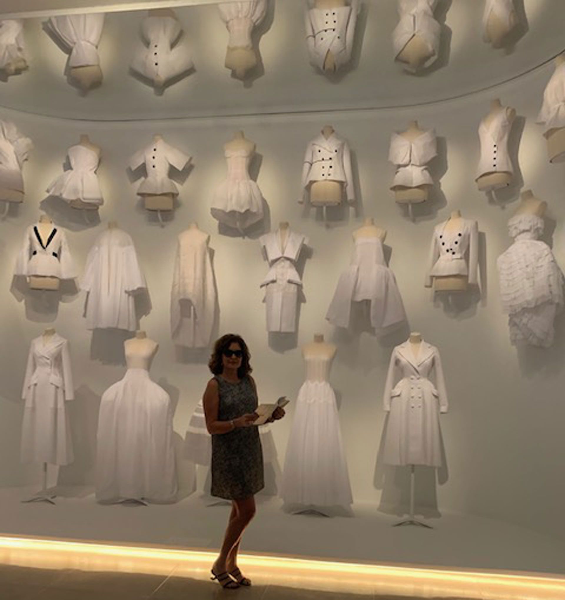Susana Milano junto a los diseños de Dior en blanco en la exposición en Dallas