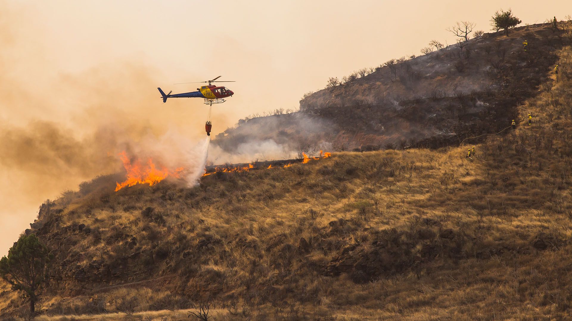 Un helicóptero hidrante intenta frenar las llamas en la isla española de la Gran Canaria (REUTERS/Borja Suarez)