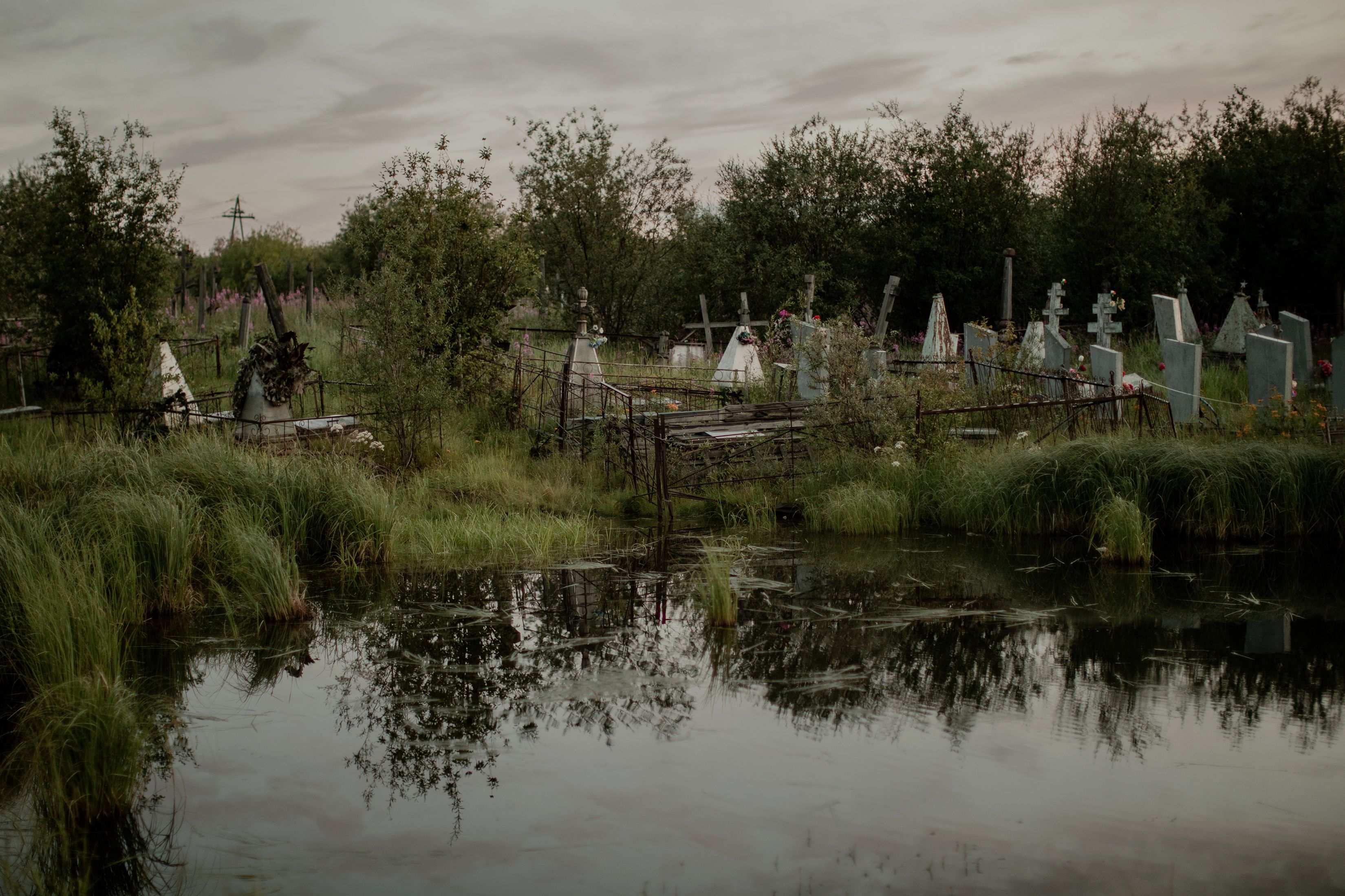 El agua inundó el cementerio en Srednekolimsk y afectó las tumbas. (Emile Ducke/The New York Times)