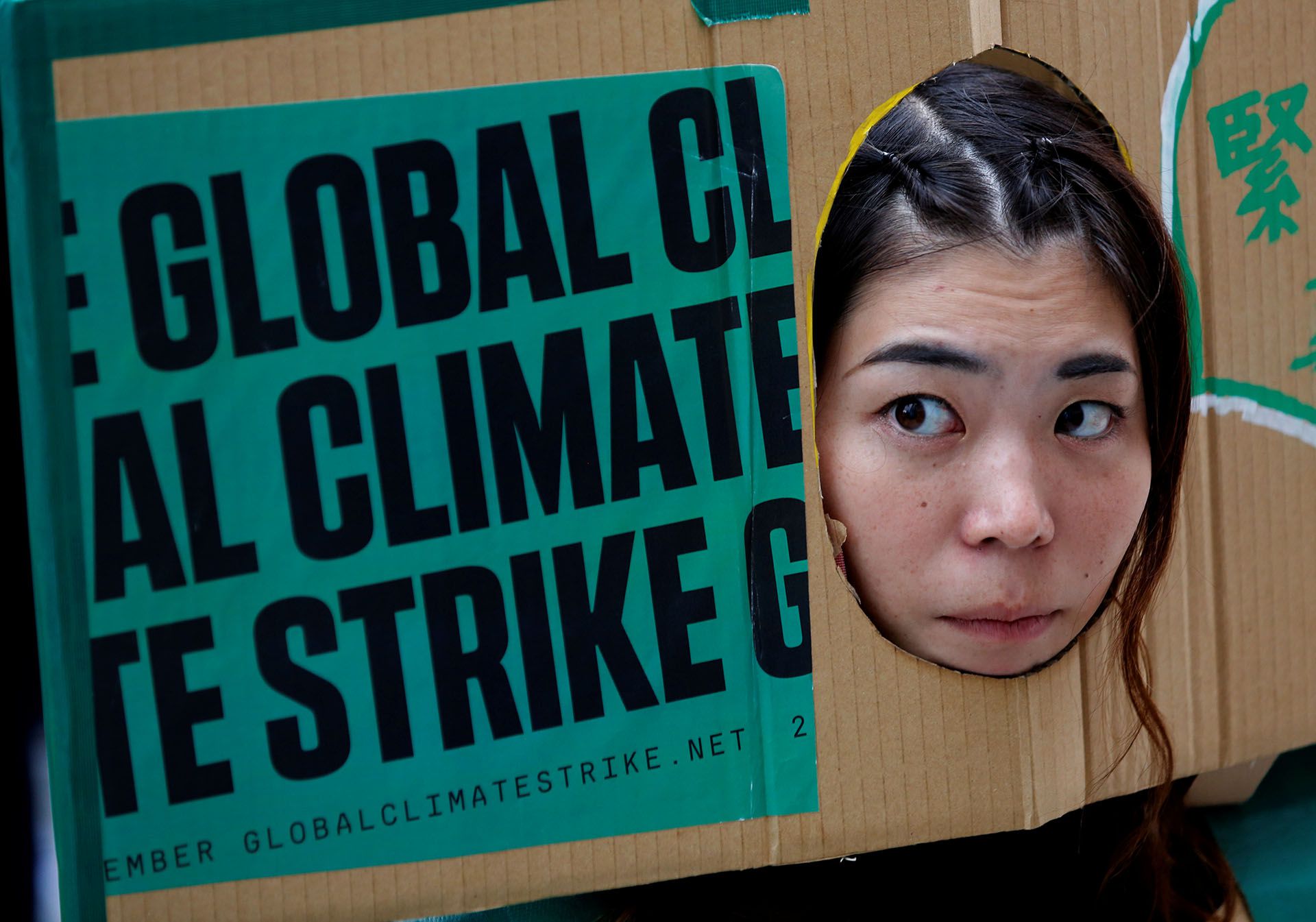 Una mujer asoma su rostro a través de una pancarta en la huelga climática celebrada en Tokio, Japón (REUTERS/Kim Kyung-Hoon)