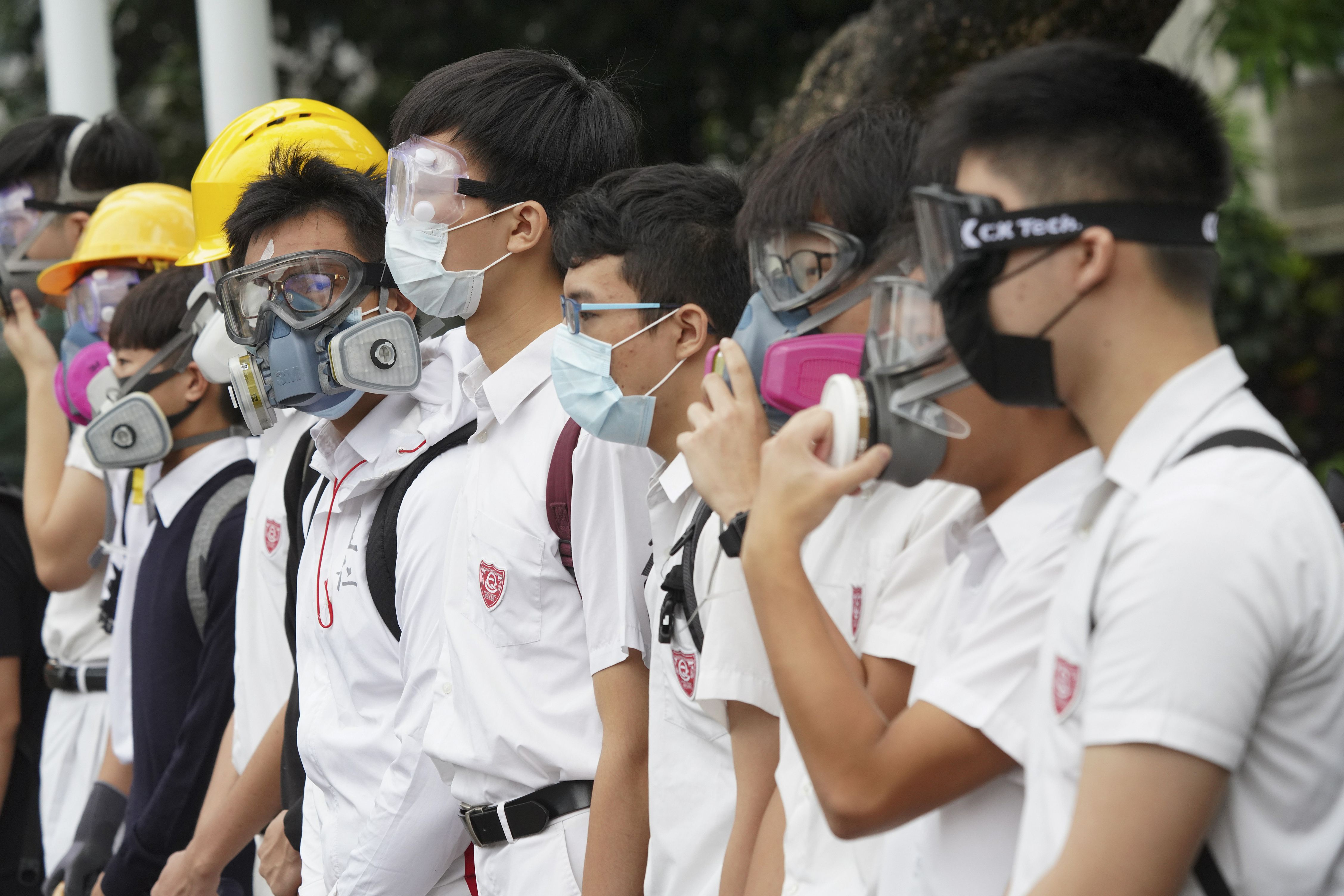 Estudiantes con máscaras de gas y cascos marchan ante el Queen’s College en Hong Kong, el lunes 2 de septiembre de 2019. (AP Foto)