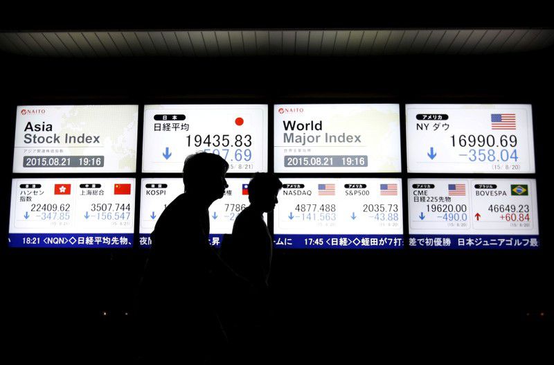 Imagen de archivo de gente caminando frente a una pantalla electrónica que muestra precios de las acciones de varios países de Asia y de los principales índices mundiales afuera de una correduría en Tokio, Japón. 21 de agosto, 2015. REUTERS/Issei Kato/Archivo