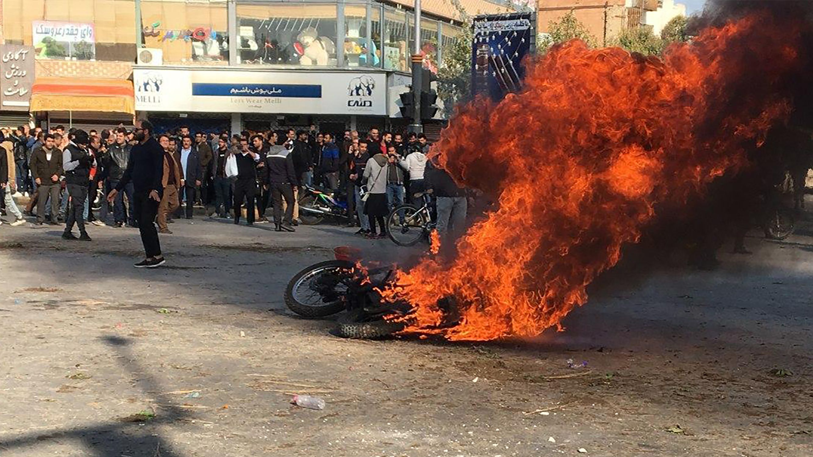 Iranian protesters gather around a burning motorcycle during a demonstration against an increase in gasoline prices in the central city of Isfahan, on November 16, 2019. - One person was killed and others injured in protests across Iran, hours after a surprise decision to increase petrol prices by 50 percent for the first 60 litres and 300 percent for anything above that each month, and impose rationing. Authorities said the move was aimed at helping needy citizens, and expected to generate 300 trillion rials ($2.55 billion) per annum. (Photo by - / AFP)