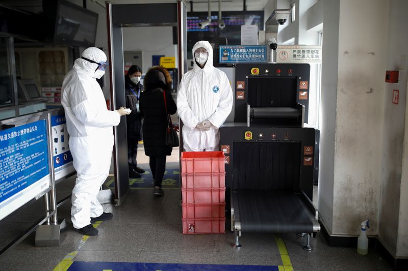 Foto del martes de trabajadores con trajes protectores cerca de un puesto de control de seguridad en una estación de metro en Pekín. Ene 28, 2020. REUTERS/Carlos Garcia Rawlins