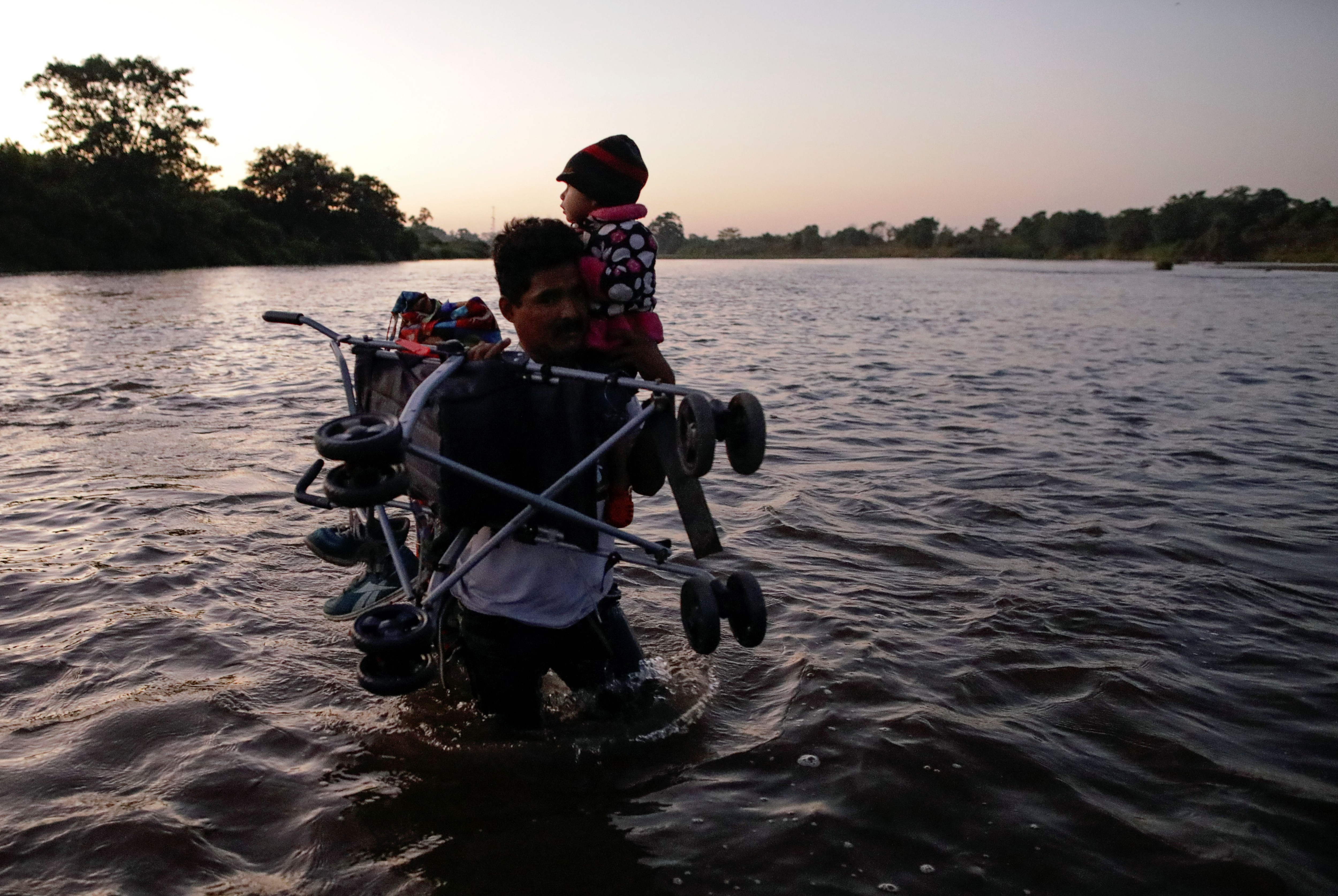 A man carries a baby and a stroller as other migrants, mainly from Central America, marching in a caravan cross the Suchiate river on the outskirts of Ciudad Hidalgo, Mexico January 23, 2020. REUTERS/Andres Martinez Casares