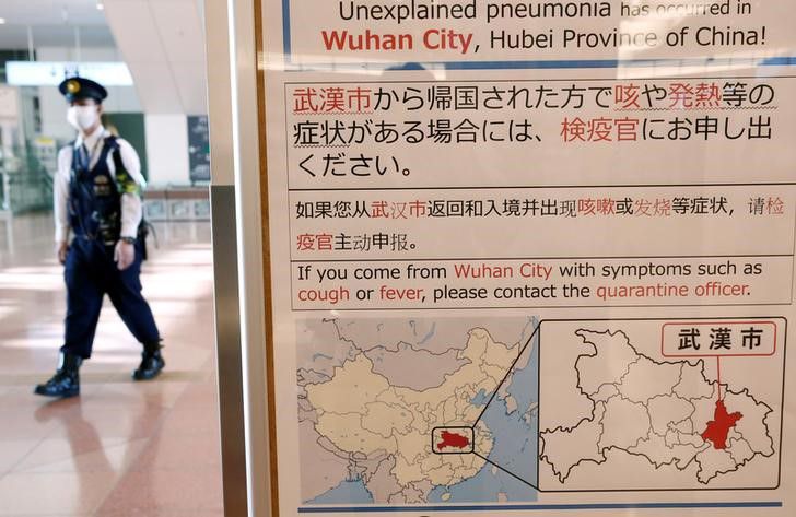 Foto de archivo de un policía con una mascarilla pasando cerca de un cartel que informa sobre el brote de coronavirus en Wuhan, China, en el aeropuerto de Haneda en Tokio. Ene 20, 2020. REUTERS/Kim Kyung-Hoon