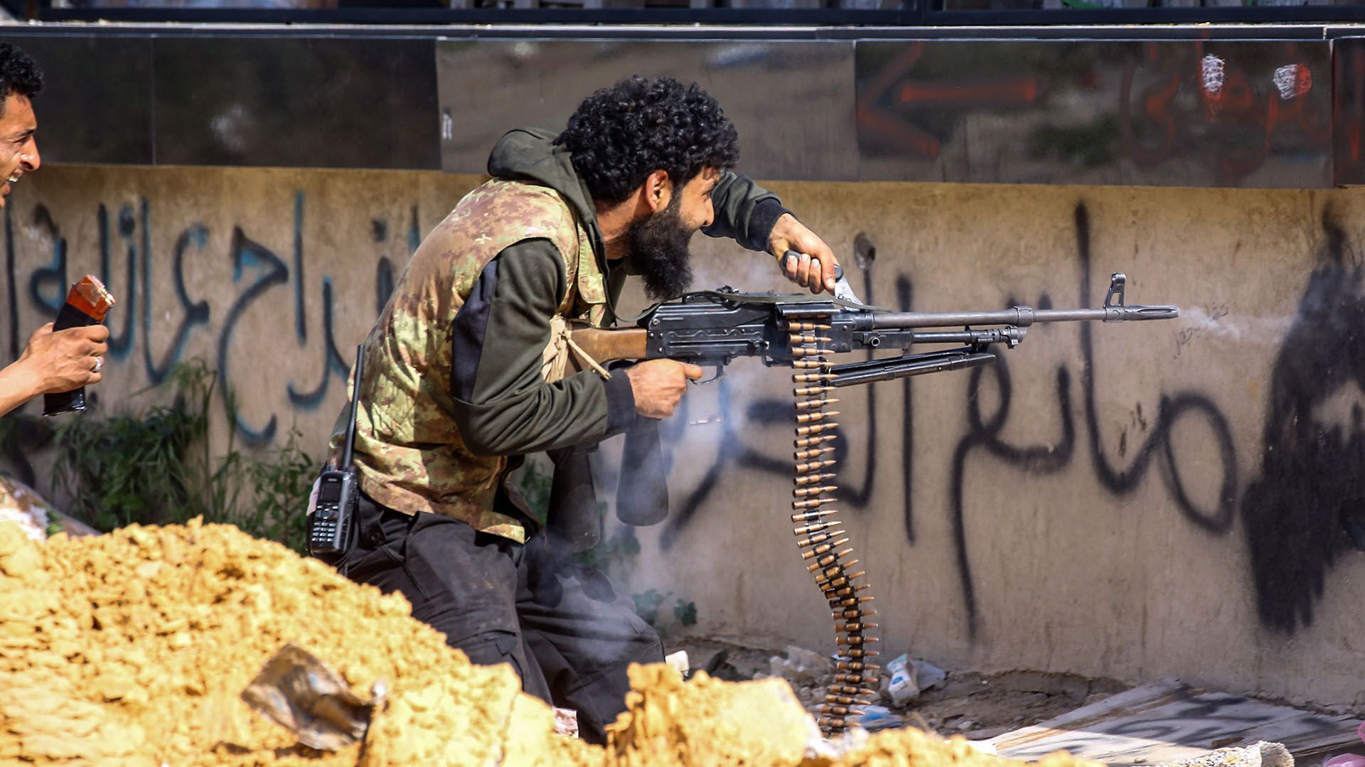 Un combatiente leal al Gobierno de Acuerdo Nacional dispara una ametralladora durante los enfrentamientos con las fuerzas de Haftar en el suburbio de Aoli Zara, en Trípoli, el 10 de abril (AFP)
