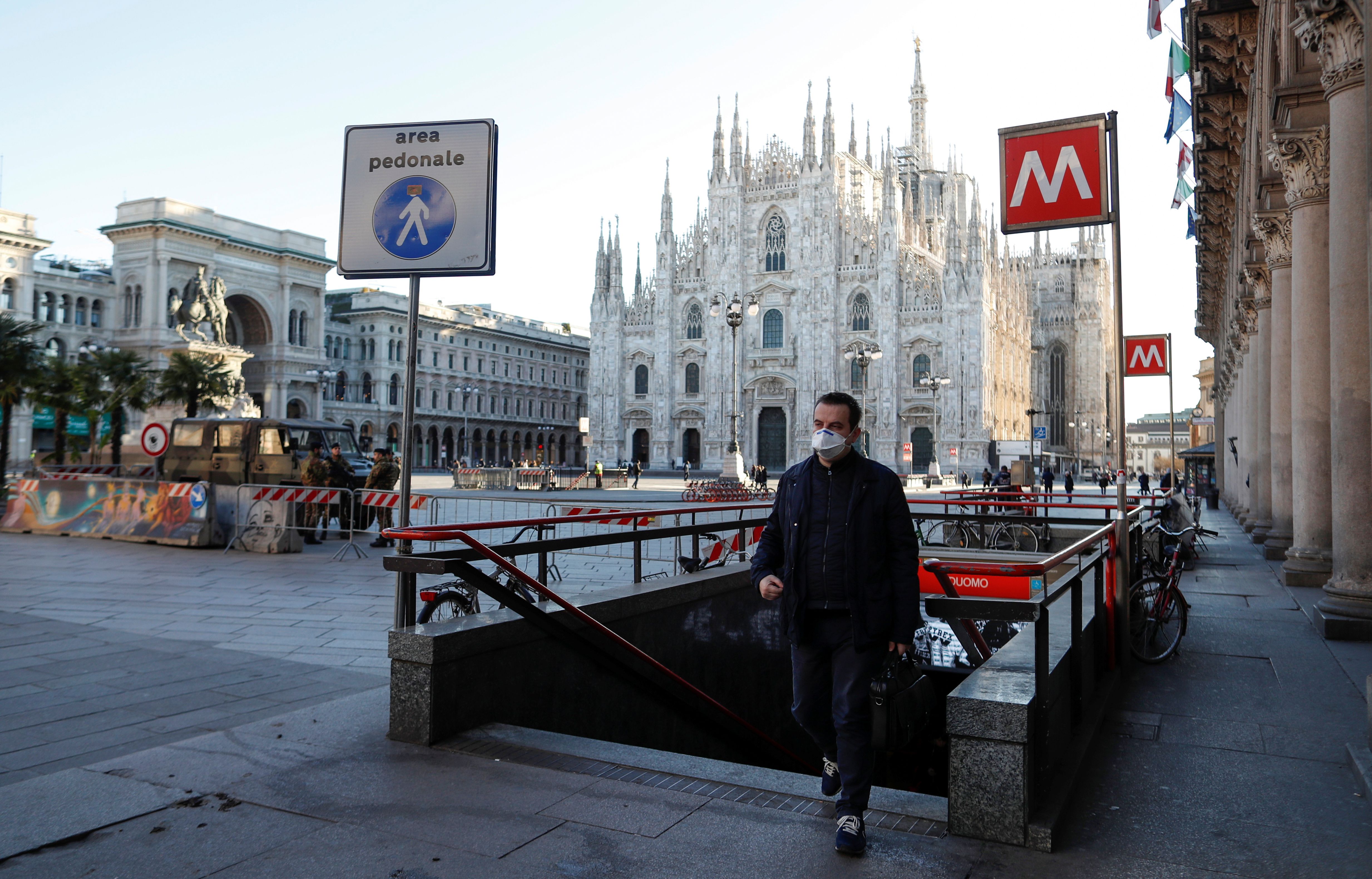 Un hombre con una máscara facial protectora camina en Milán, Italia, junto a una plaza del Duomo casi vacía, normalmente llena de gente, mientras un brote de coronavirus en el norte de Italia sigue creciendo (REUTERS/Yara Nardi)