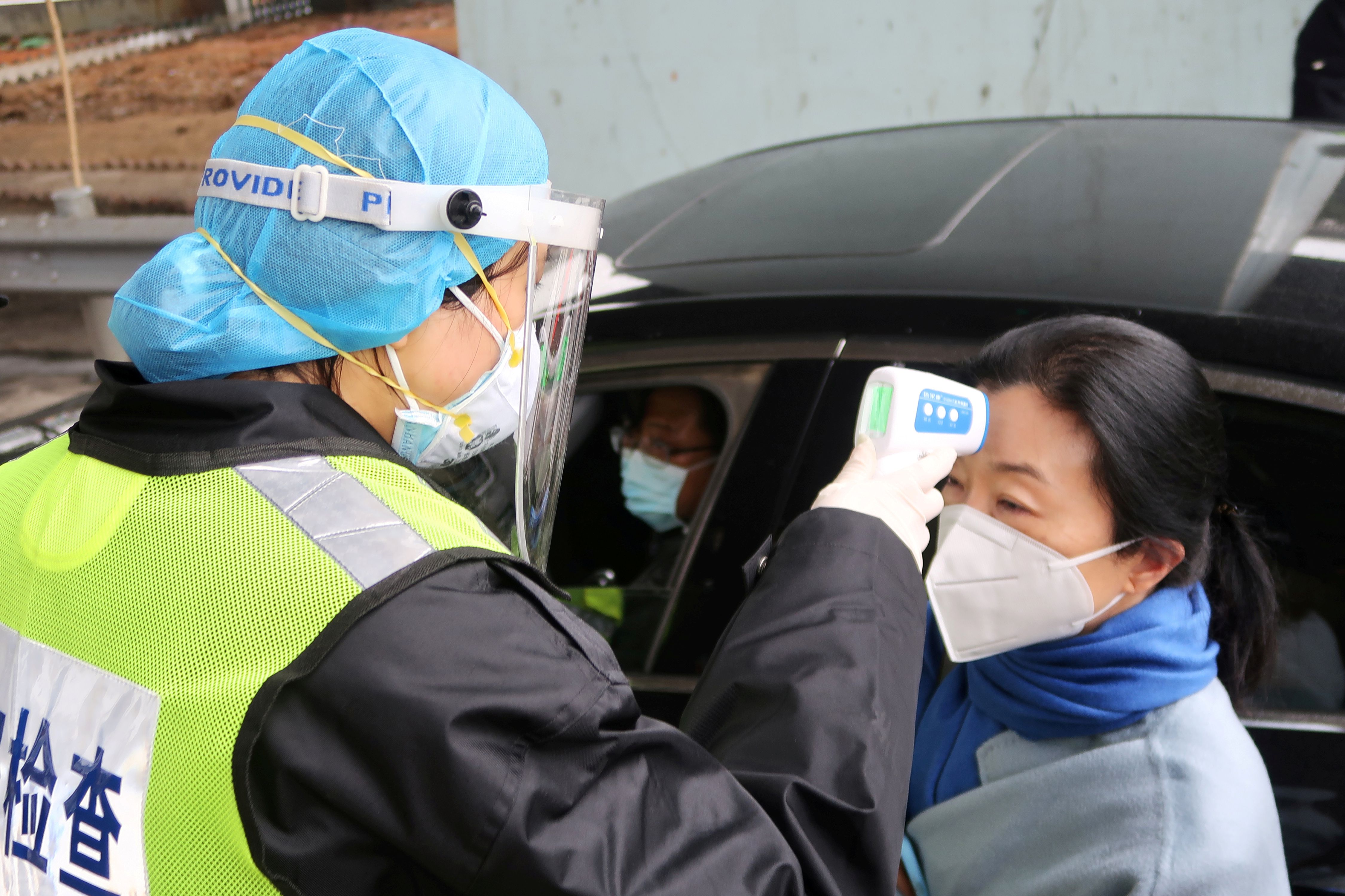 Un oficial de seguridad chequea la temperatura de un pasajero en Xianning, cerca de Wuhan (REUTERS/Martin Pollard)