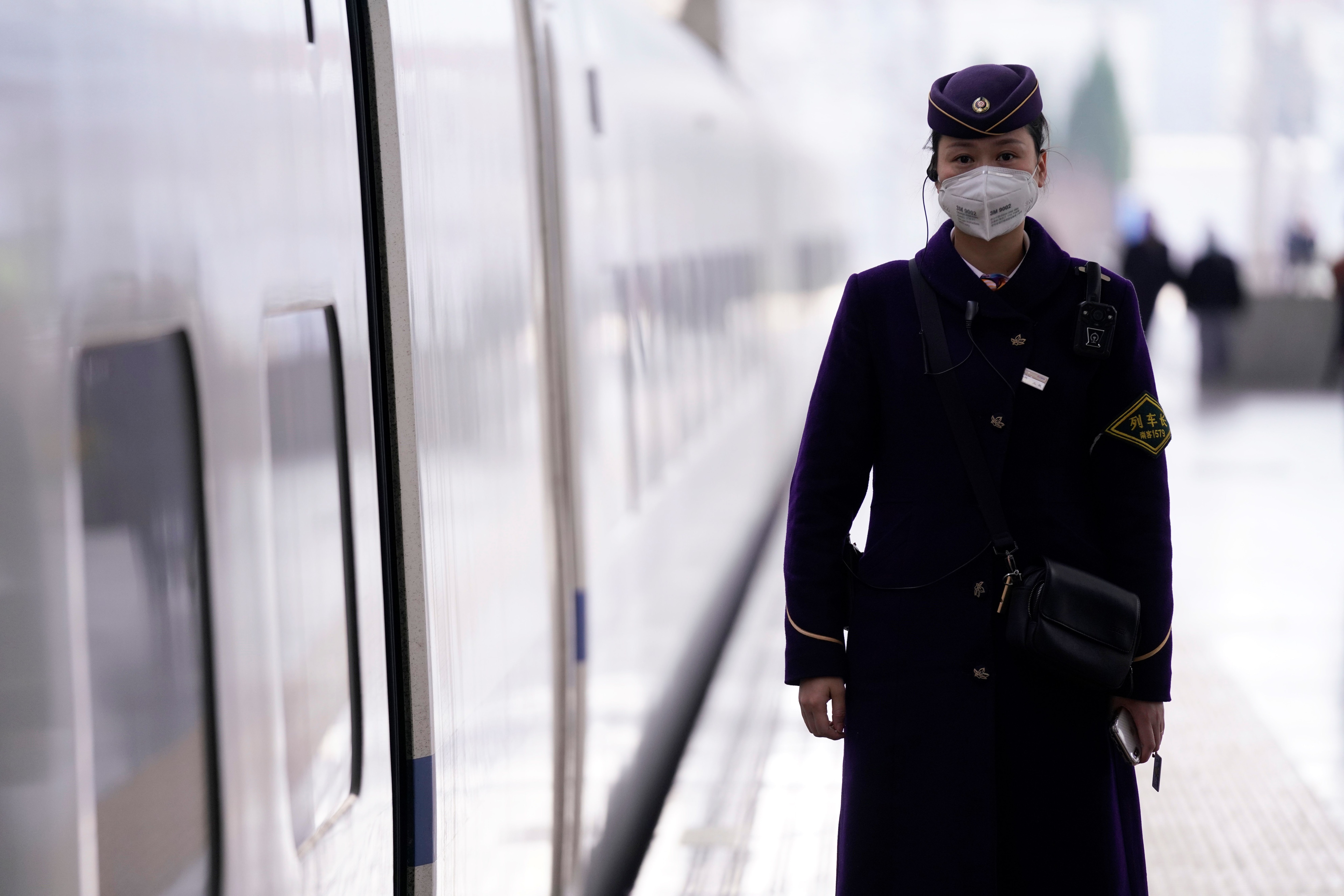 Una mujer del personal del metro de Shanghai en China, usa una mascarilla para protegerse del coronavirus