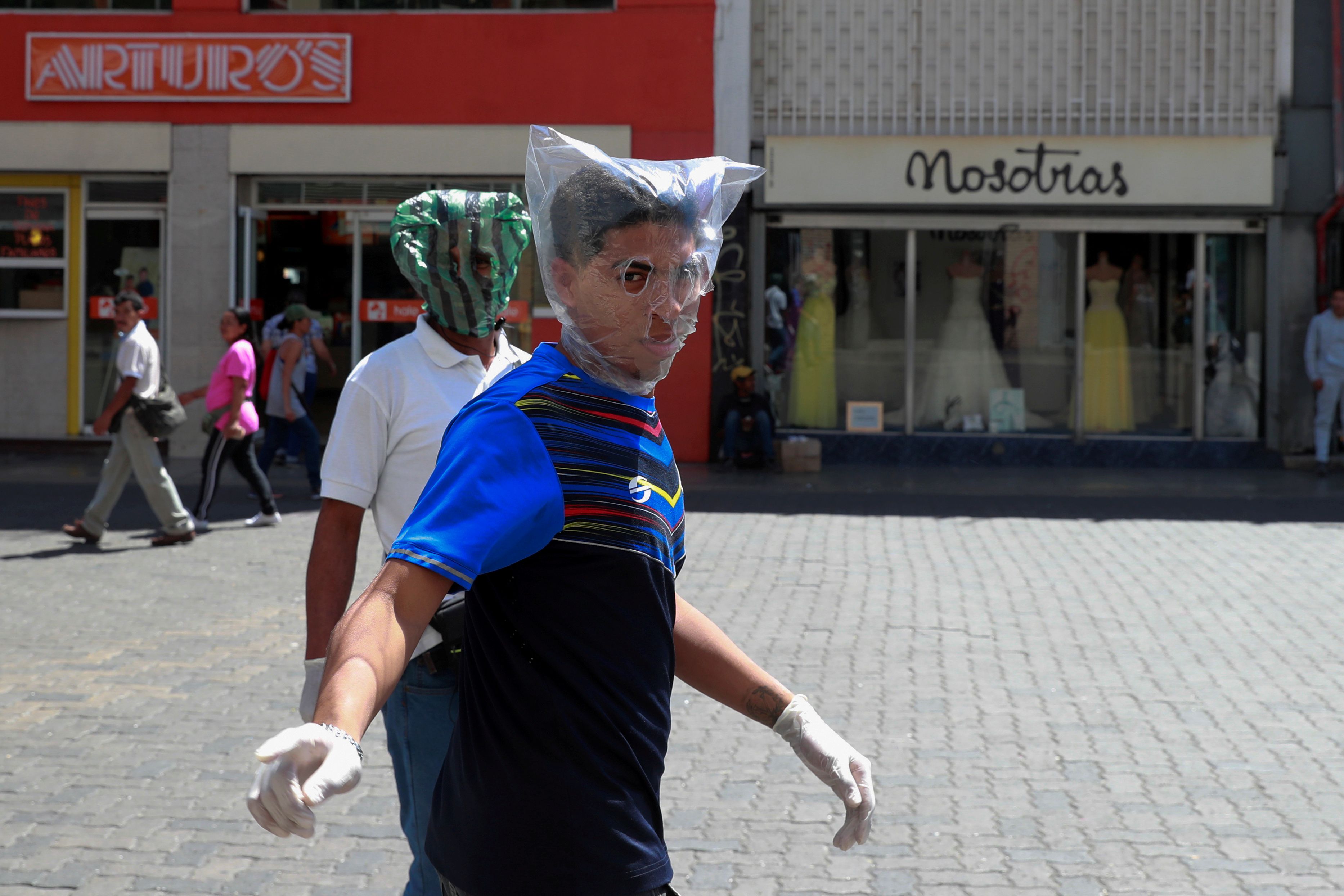 Dos ciudadanos se protegen con bolsas de plástico en Caracas (REUTERS/Carlos Jasso)