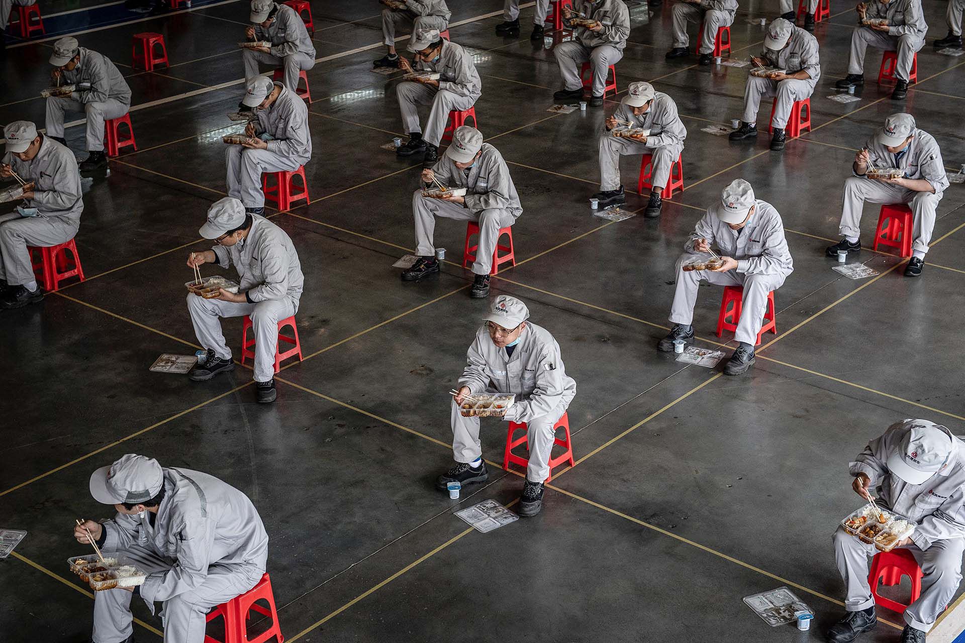Empleados a la hora del almuerzo en una fábrica de automoviles, Honda, en Wuhan, donde comenzó la pandemia y esta semana fueron autorizados a regresar a sus trabajos. 