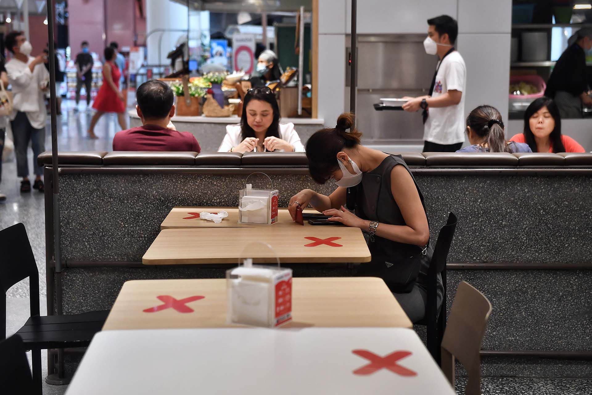 Las cruces señalan los lugares a evitar para mantener la distancia social en el patio de comidas de un centro comercial en Bangkok. 