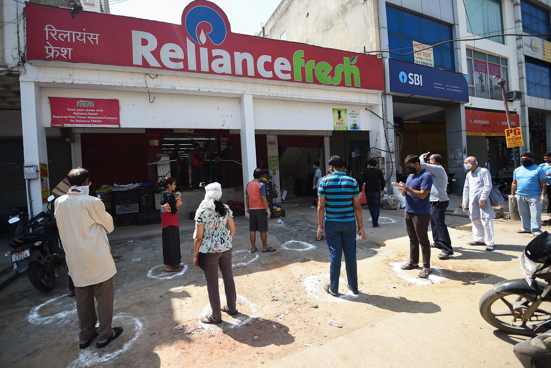 Personas hacen fila frente a un mercadillo en Faridabad, India. 