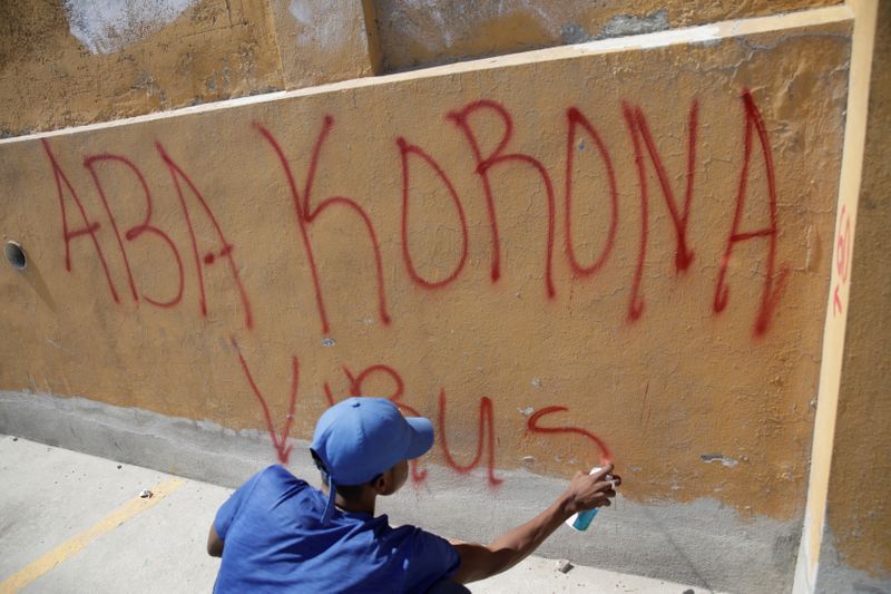 Un manifestante pinta un graffiti fuera del Hotel Monte Cristo, designado como instlación de cuarentena en momentos en que el coronavirus se expande en el mundo. Puerto Príncipe, Haití, 12 de marzo de 2020. REUTERS/Andres Martinez Casares