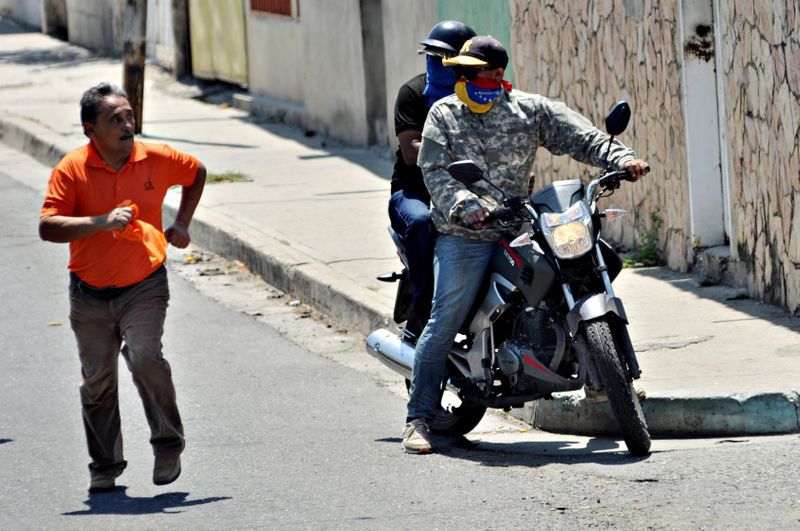 Foto del sábado. Un partidario del líder de la oposición venezolana, Juan Guaidó, corre cuando se le acercan motoristas durante una manifestación en Barquisimeto, Venezuela. 29 de febrero de 2020. REUTERS/Juan Calero. NO DISPONIBLE PARA REVENTA NI ARCHIVO.
