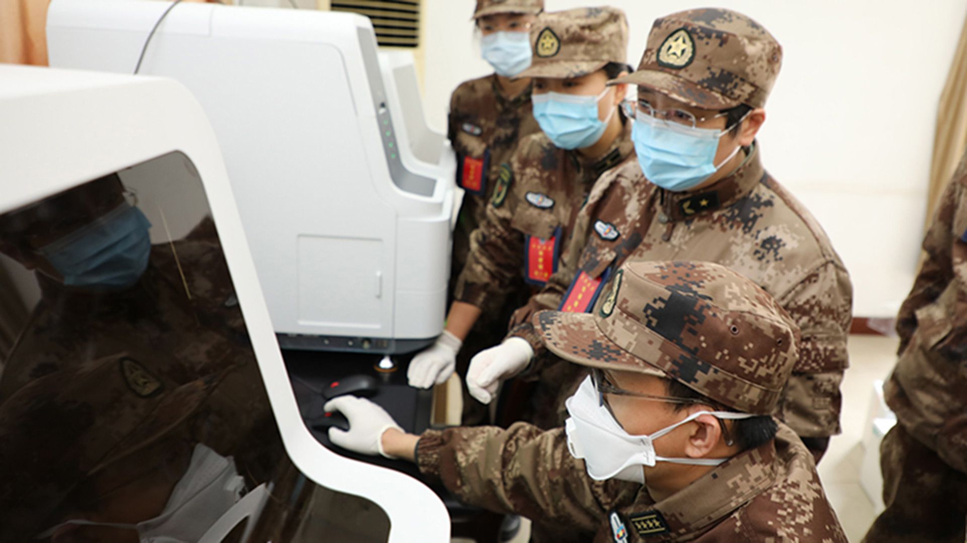 Científicos militares chinos observan un monitor en un laboratorio en el que se investiga los alcances del coronavirus COVID-19 (AMMS)