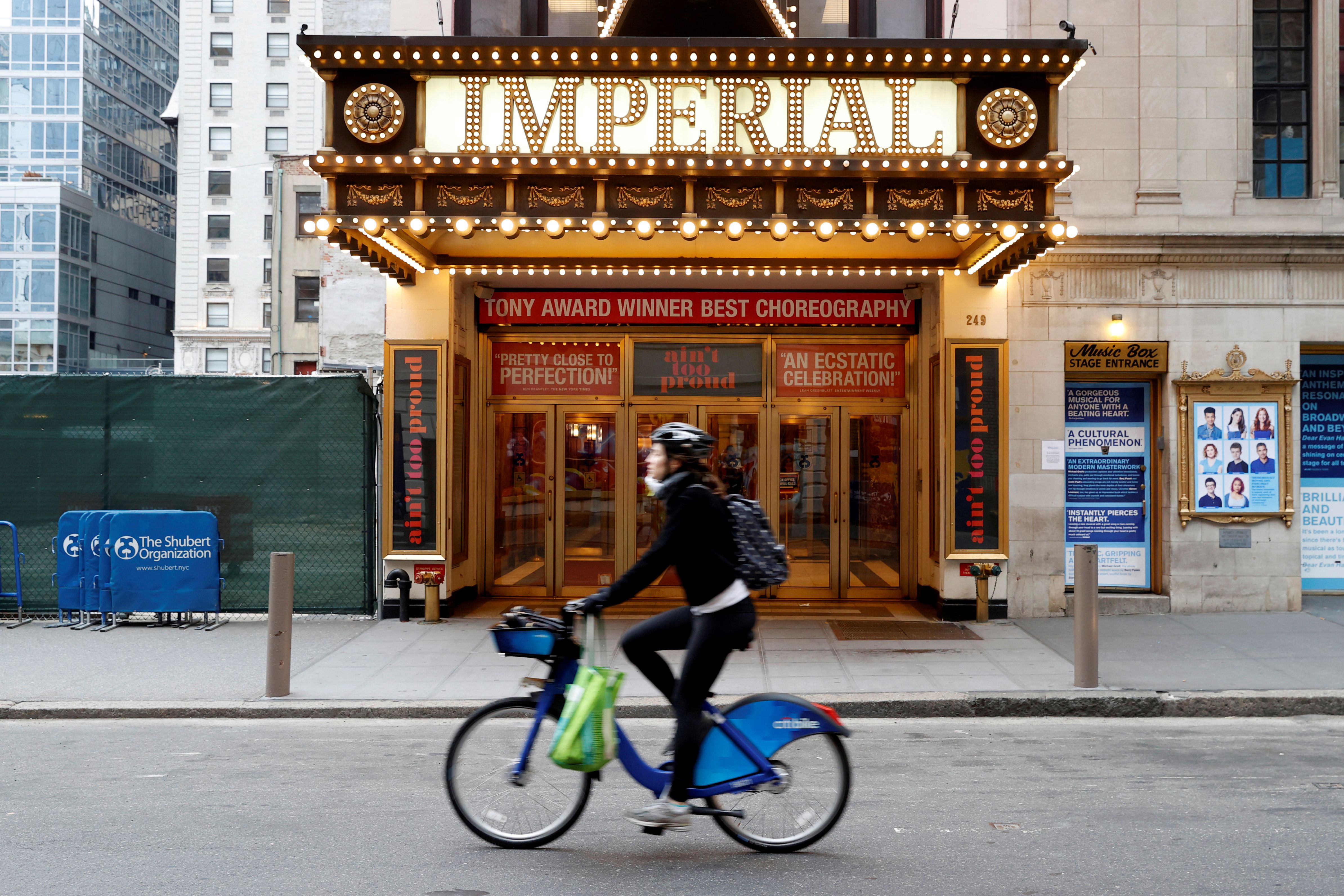 Una mujer circula en bicileta frente al Imperial Theatre, cerrado, en Times Square (REUTERS/Mike Segar)