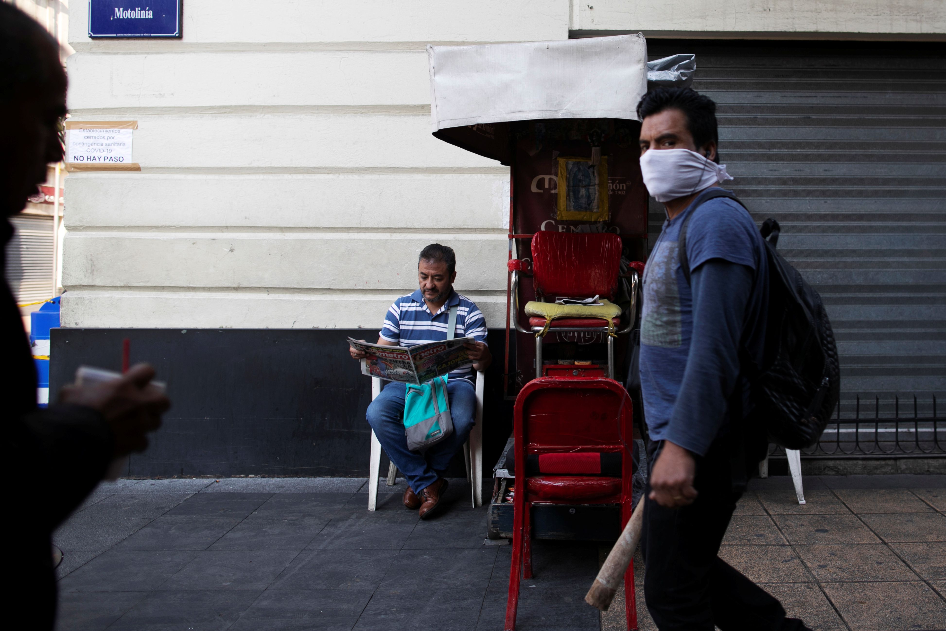 A shoe shiner reads the paper as he waits for costumers in one of the main streets in downtown as Mexico's government declared a health emergency and issued stricter rules to curb the spread of the coronavirus disease (COVID-19), in Mexico City, Mexico April 3, 2020. REUTERS/Carlos Jasso