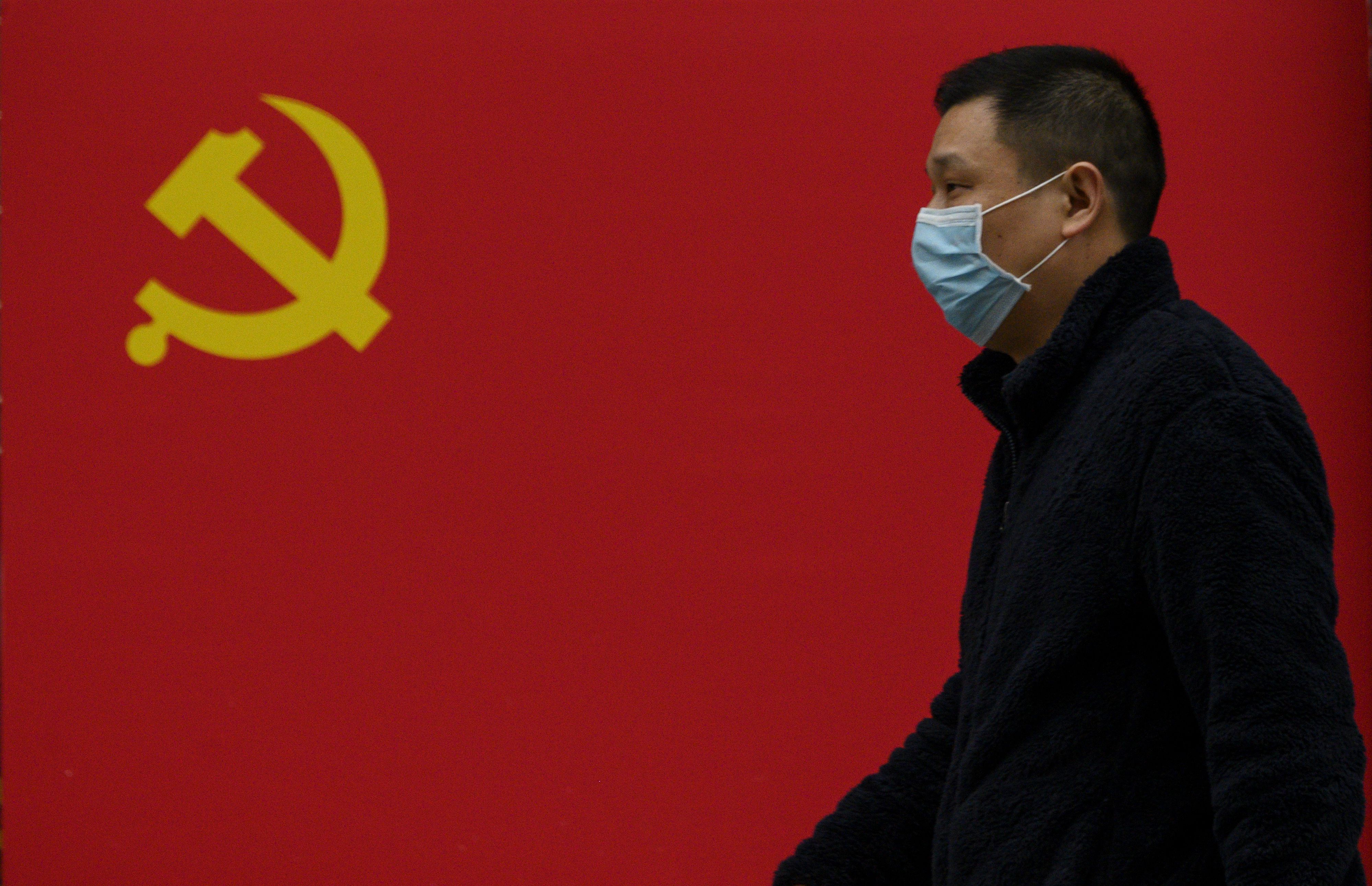 Un hombre pasa frente a una bandera del Partido Comunista en una calle de Wuhan (NOEL CELIS / AFP)