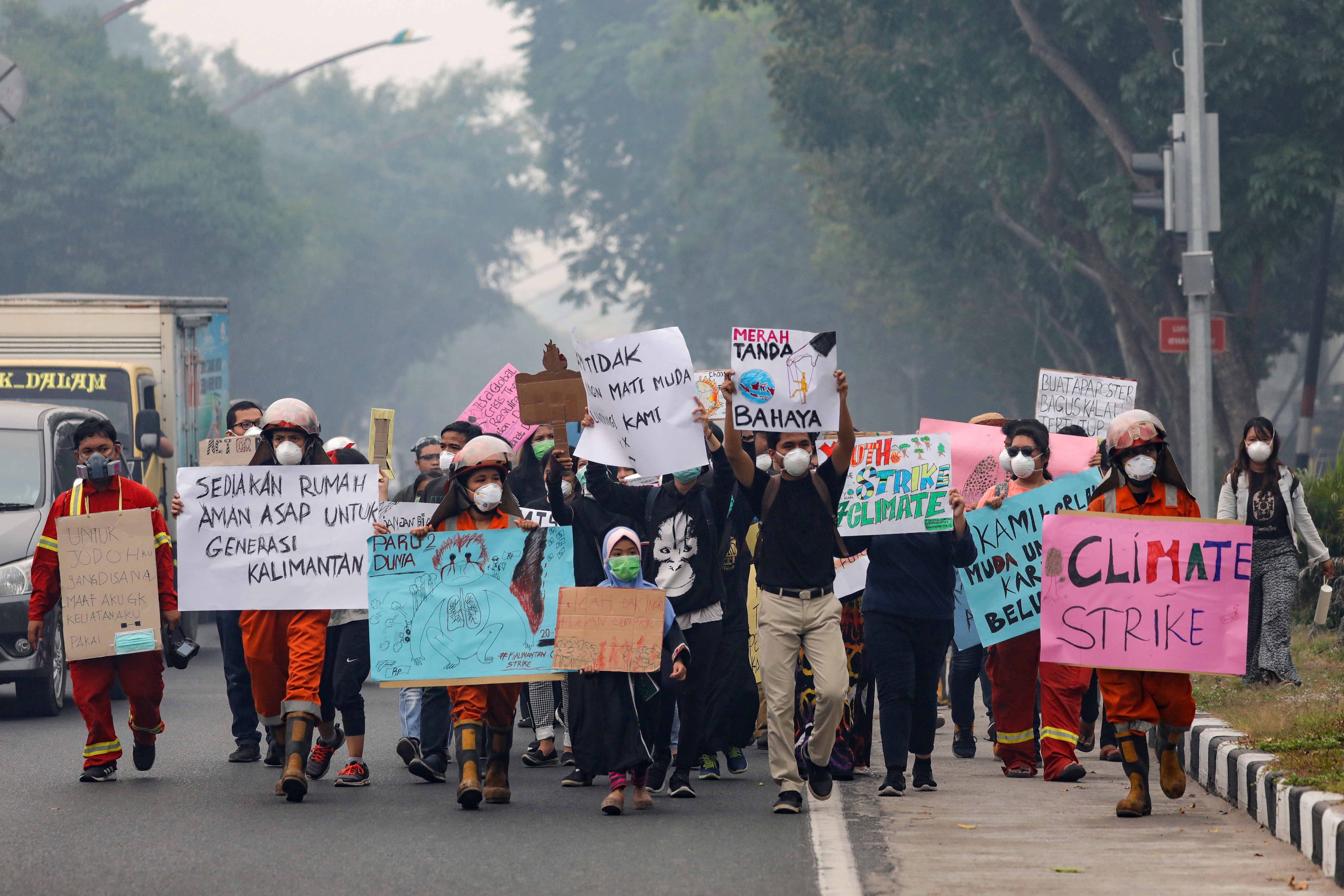 Jóvenes caminan con pancartas durante una manifestación de la huelga climática mundial mientras el smog cubre la ciudad debido a los incendios forestales en Palangka Raya, provincia de Kalimantan Central, Indonesia, el 20 de septiembre de 2019. REUTERS/Willy Kurniawan