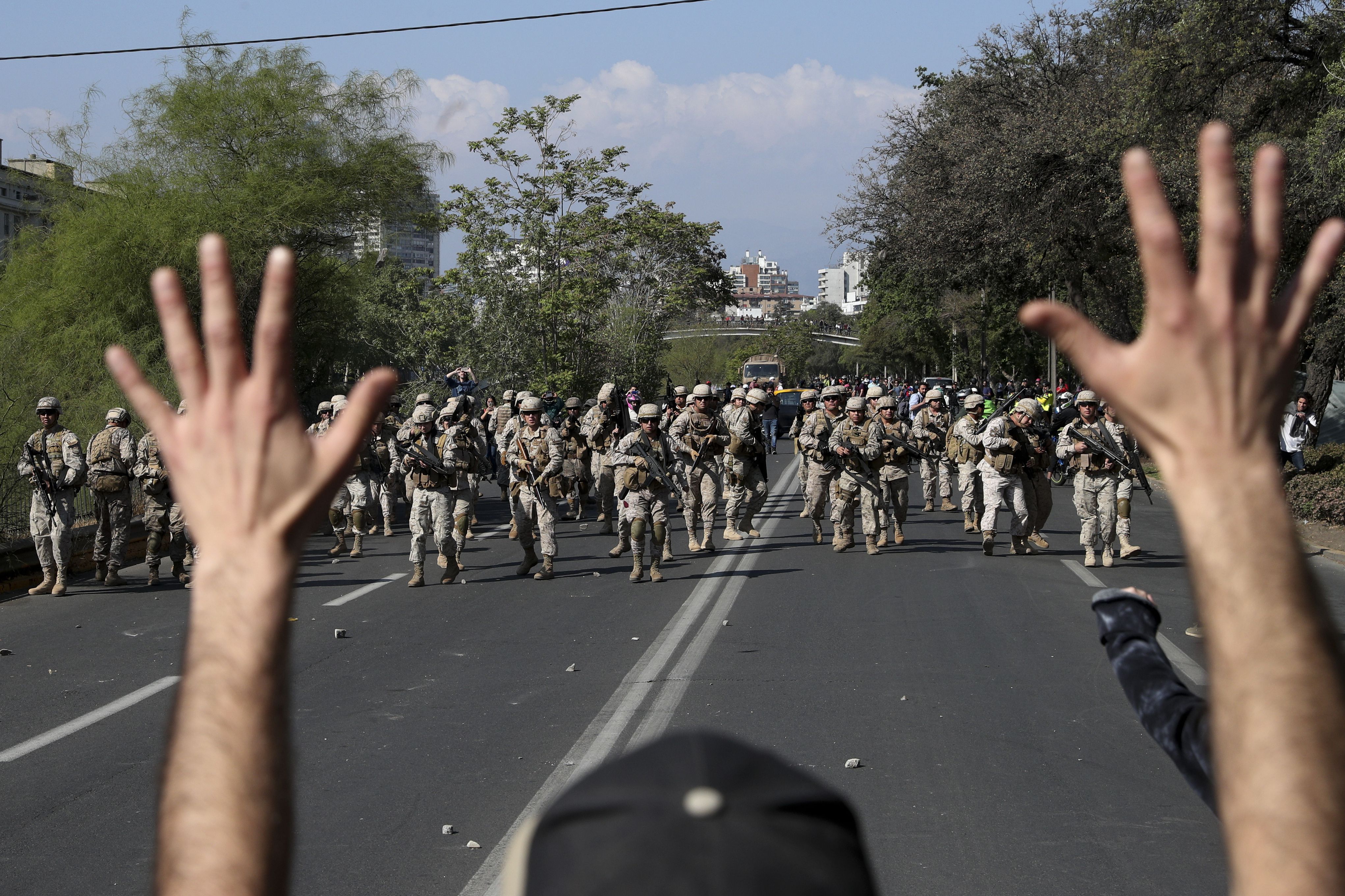 Un manifestante levanta los brazos ante el avance de soldados en Santiago (AP)