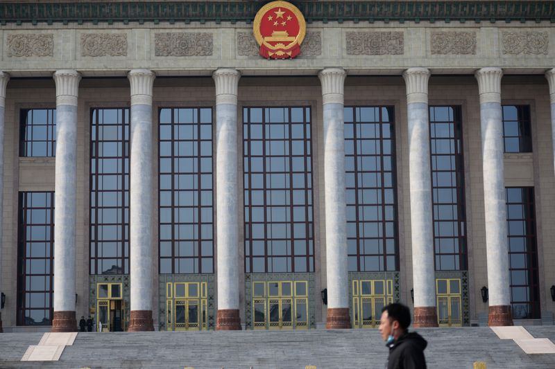 FOTO DE ARCHIVO: Un hombre con mascarilla pasa por el Gran Salón del Pueblo en Pekín, China, el 19 de febrero de 2020. REUTERS/Tingshu Wang