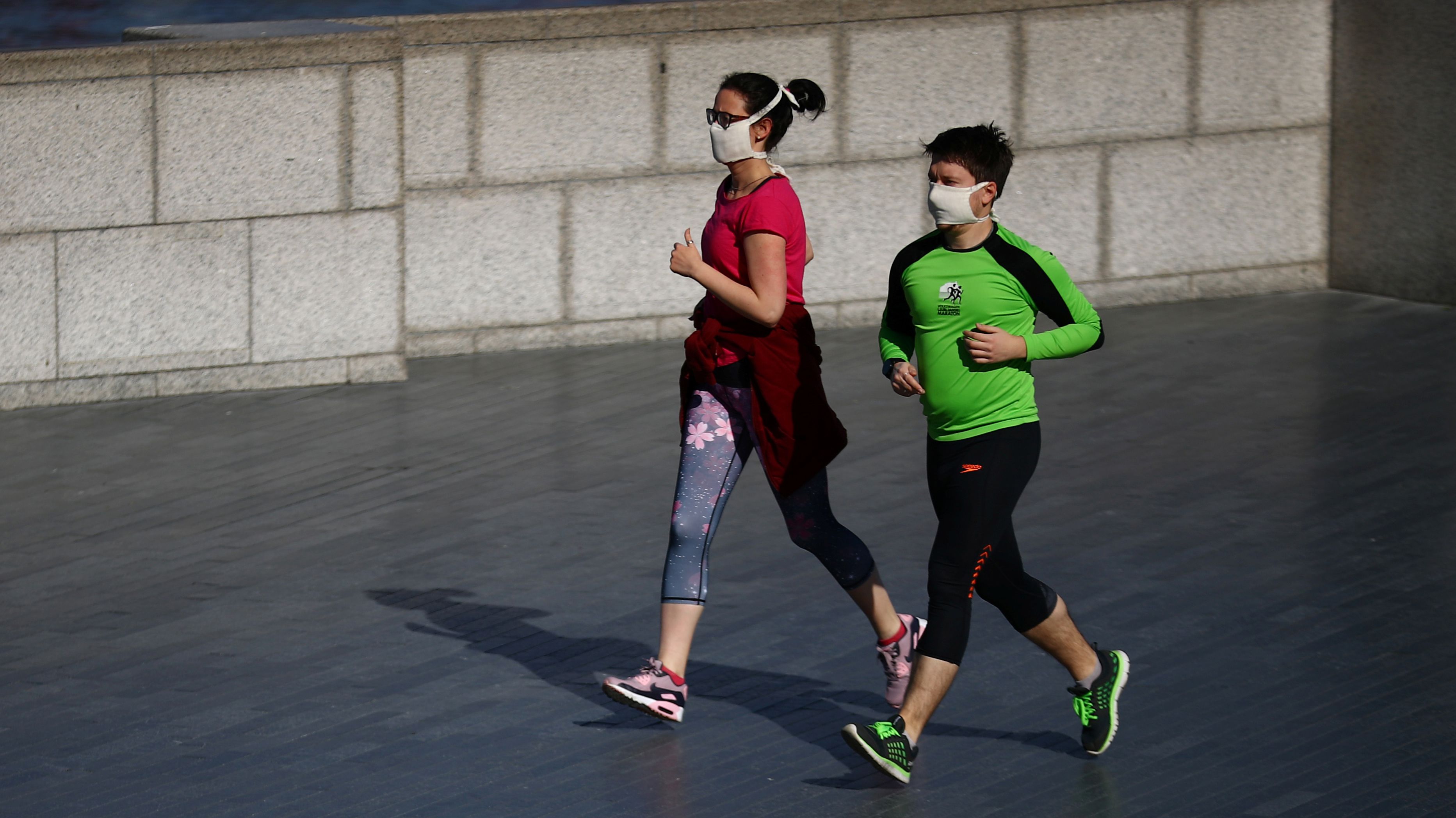 People jog wearing protective face masks by the River Thames, as the spread of the coronavirus disease (COVID-19) continues, London, Britain, March 24, 2020. REUTERS/Hannah McKay