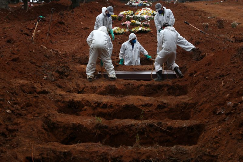 Sepultureros con trajes protectores entierran el ataúd de José Soares, de 48 años, quien murió a causa de la enfermedad por coronavirus (COVID-19), en el cementerio de Sao Luiz, en Sao Paulo, Brasil, 4 junio 2020 (REUTERS/Amanda Perobelli)