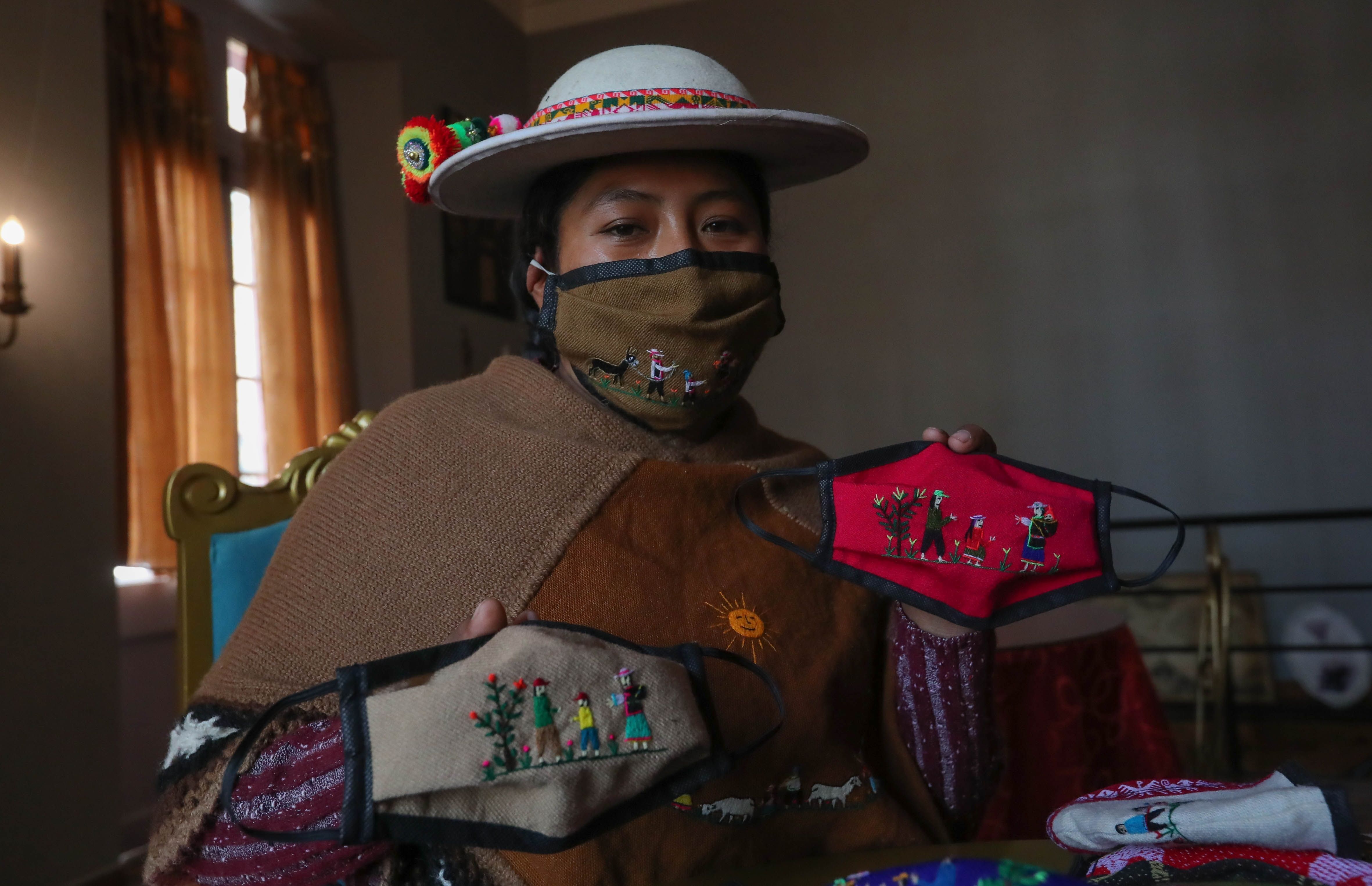 La indígena Ana Alicia Layme, de la comunidad Ayata, muestra tapabocas bordados en La Paz (Bolivia) (EFE/Martín Alipaz)