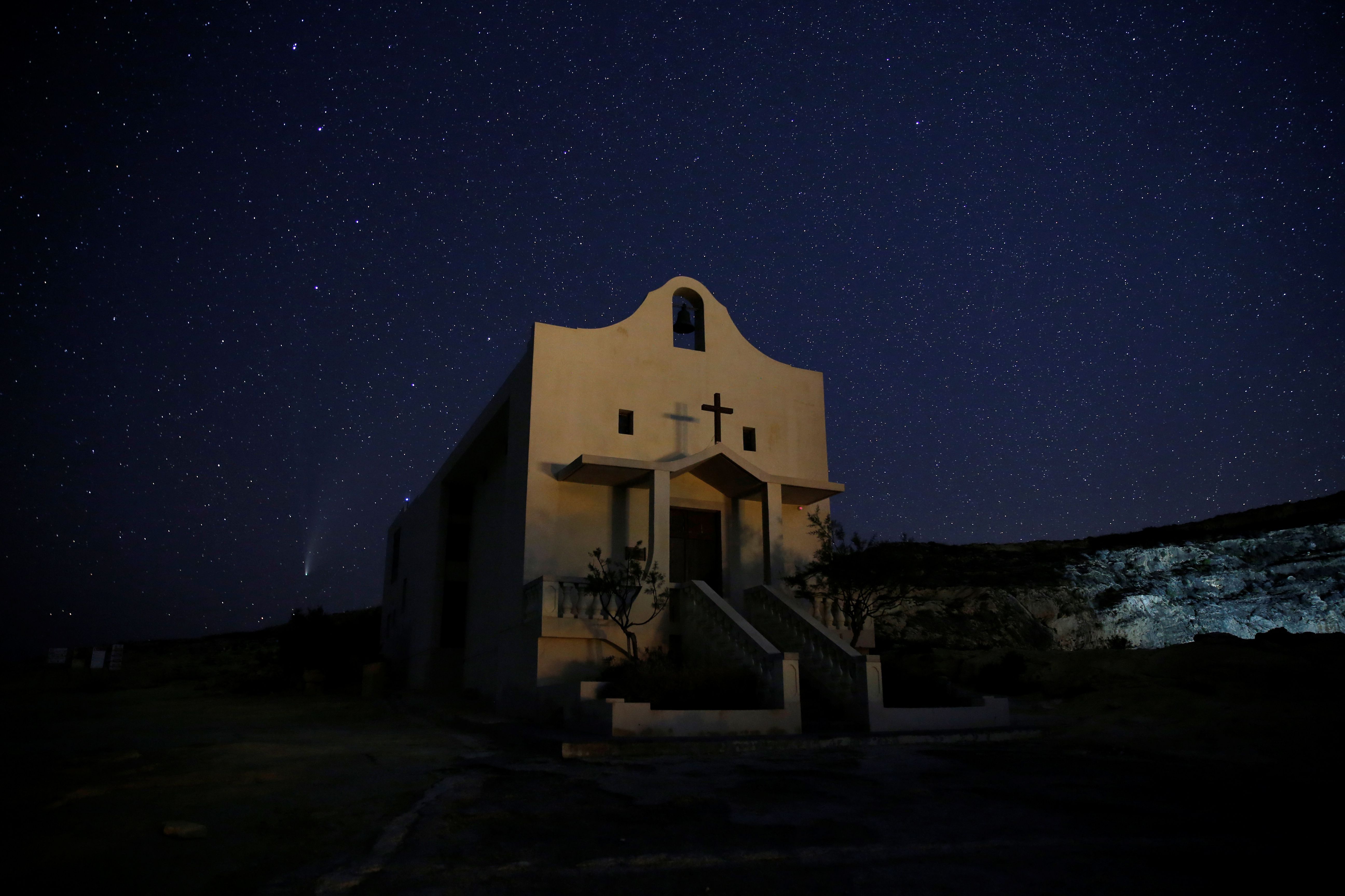El cometa Neowise se ve detrás de la capilla de Santa Ana en Dwejra, en las afueras del pueblo de San Lawrenz en la isla de Gozo, Malta, 22 de julio de 2020 (REUTERS)