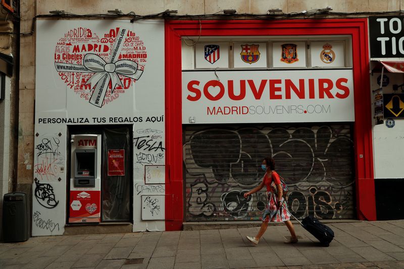 FOTO DE ARCHIVO: Una mujer con mascarilla pasa por delante de una tienda de recuerdos cerrada en Madrid, España, el 8 de julio de 2020. REUTERS/Susana Vera