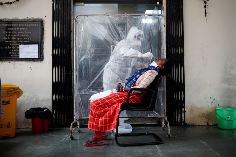 Imagen de archivo de un trabajador sanitario con equipo de protección personal recolectando una muestra con un hisopo de una mujer en un centro de salud local para realizar un examen de COVID-19, la enfermedad causada por el coronavirus, en medio de la pandemia en Nueva Delhi, India. 8 de julio, 2020. REUTERS/Adnan Abidi/Archivo