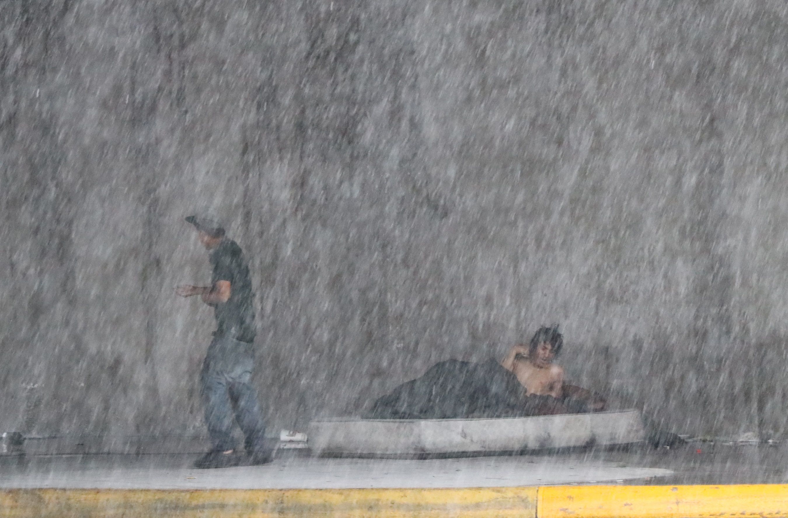 Dos habitantes de calle se protegen de la lluvia en una céntrica avenida de Monterrey (México). EFE/ María Julia Castañeda 