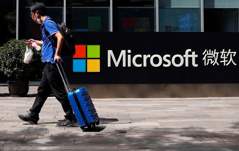 Una persona camina con su valija frente a una oficina de Microsoft en Beijing