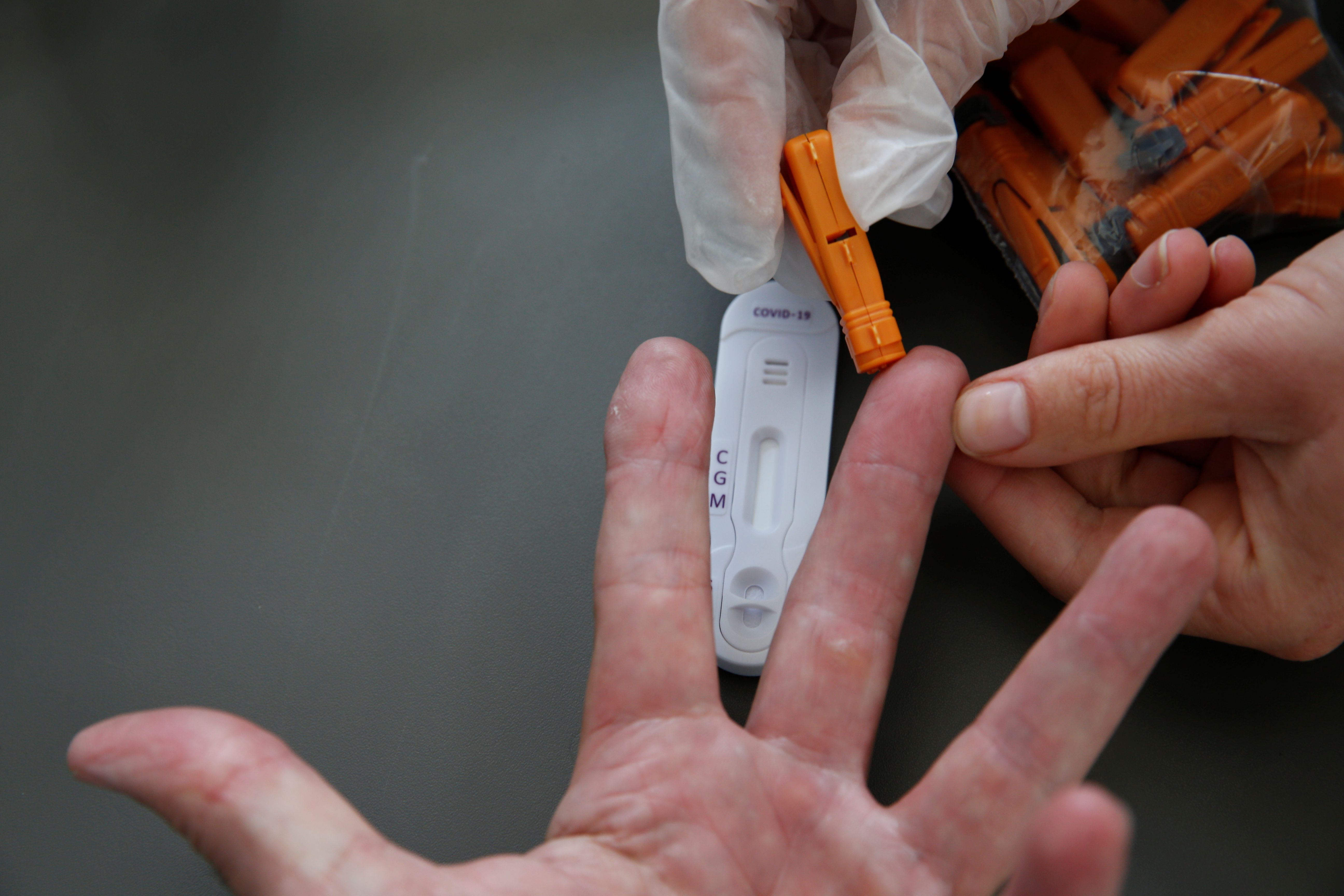 Un farmacéutico toma una muestra de sangre para una prueba de diagnóstico rápido de anticuerpos para COVID-19 en Cambrai, Francia (Reuters)