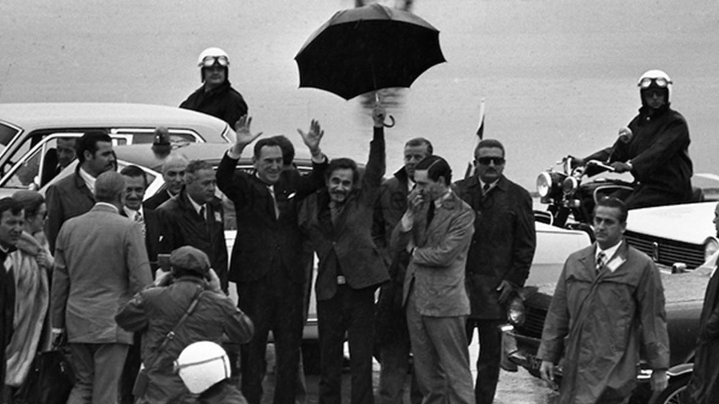 Secuencia de imágenes del regreso, luego de 18 años de exilio, de Domingo Perón a Argentina en el que José Ignacio Rucci sostiene el paraguas para protegerlo de la lluvia. También se distinguen José Lopez Rega e Isabel