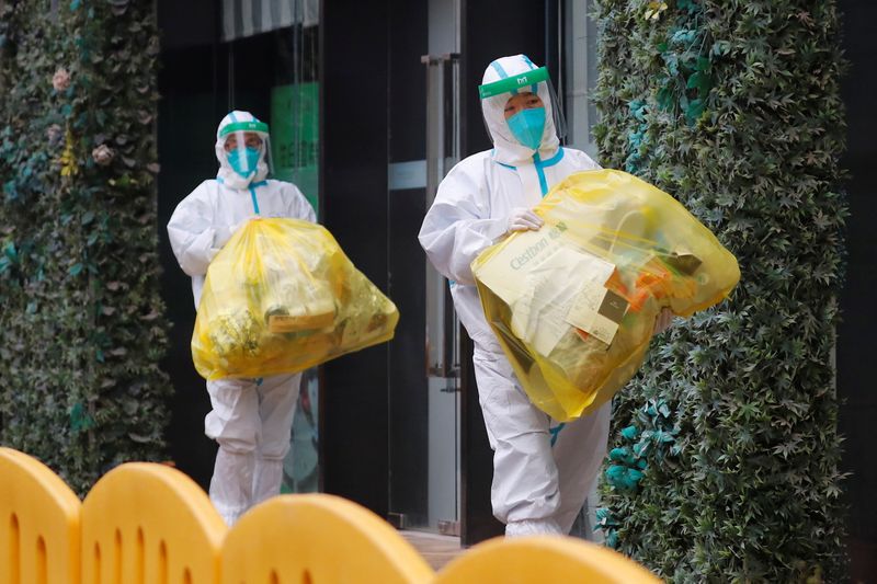 Dos trabajadores de la Organización Mundial de la Salud (OMS) con equipos de protección individual (EPI) encargados de investigar el origen del nuevo coronavirus (SARS-CoV-2) en Wuhan, provincia de Hubei, China 
