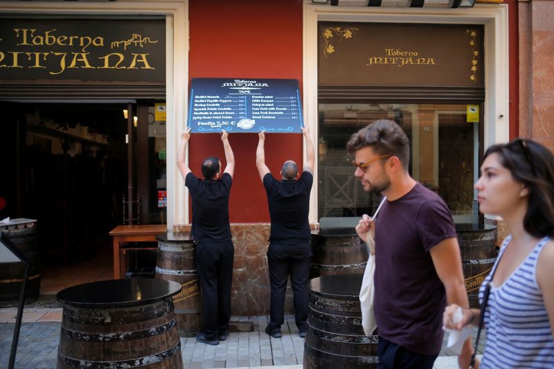 FOTO DE ARCHIVO: Dos camareros colocan un cartel en el exterior de un bar de Málaga, España, el 14 de abril de 2019. REUTERS/Jon Nazca