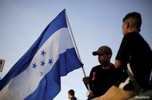 A demonstrator holds a Honduran flag during a protest to mark the first anniversary of a contested presidential election with…