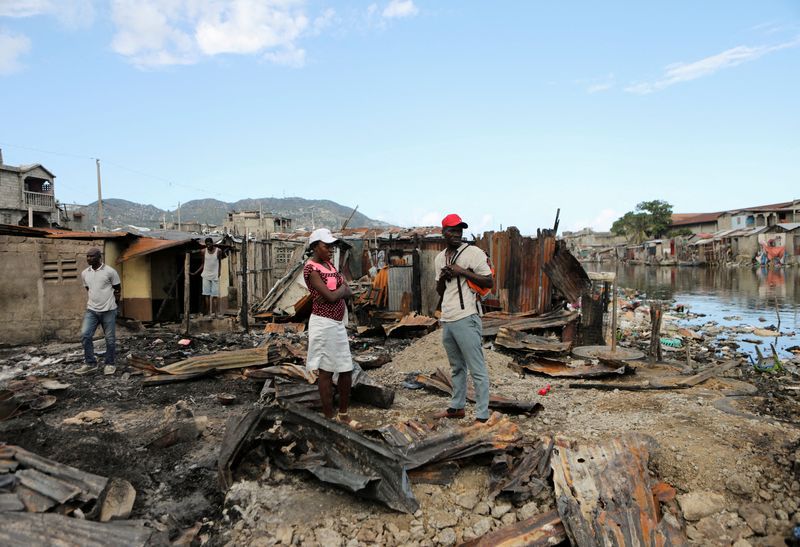 Imagen de archivo de gente parada en medio de los restos de viviendas precarias que fueron destruidas cuando un camión de combustible estalló en el vecindario, matando a decenas de personas, en Cabo Haitiano, Haití. 14 de diciembre, 2021. REUTERS/Ralph Tedy Erol/Archivo