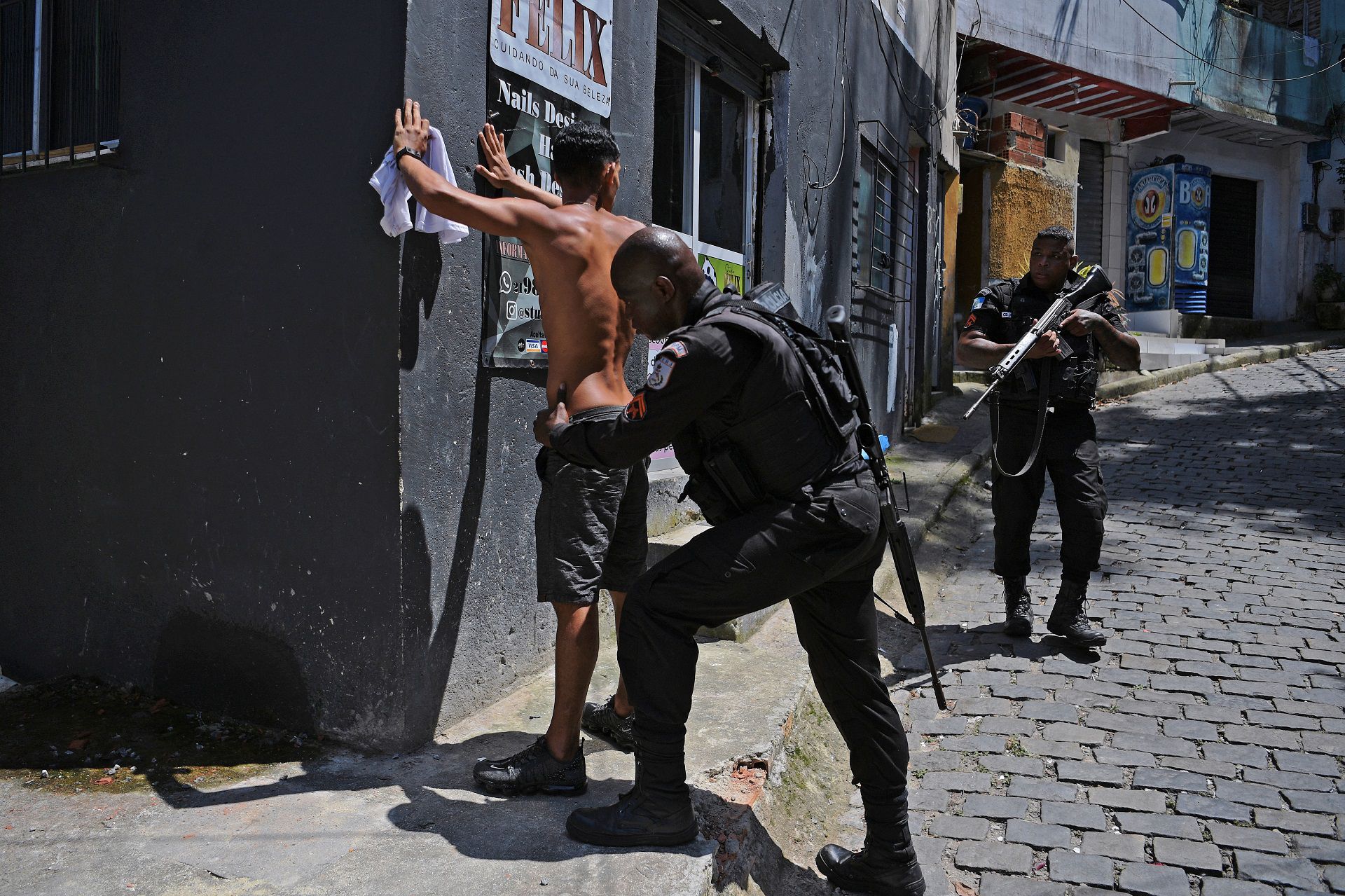 (FILES) In this file photo taken on January 20, 2022, a member of the Brazilian Military Police frisks a suspect during a large scale operation against drug trafficking and militias, to occupy and secure parts of the Morro do Banco favela in Rio de Janeiro, Brazil. - The governor of Rio de Janiero Claudio Castro announced on Saturday, January 22, a security and social development program for the favelas. (Photo by CARL DE SOUZA / AFP)