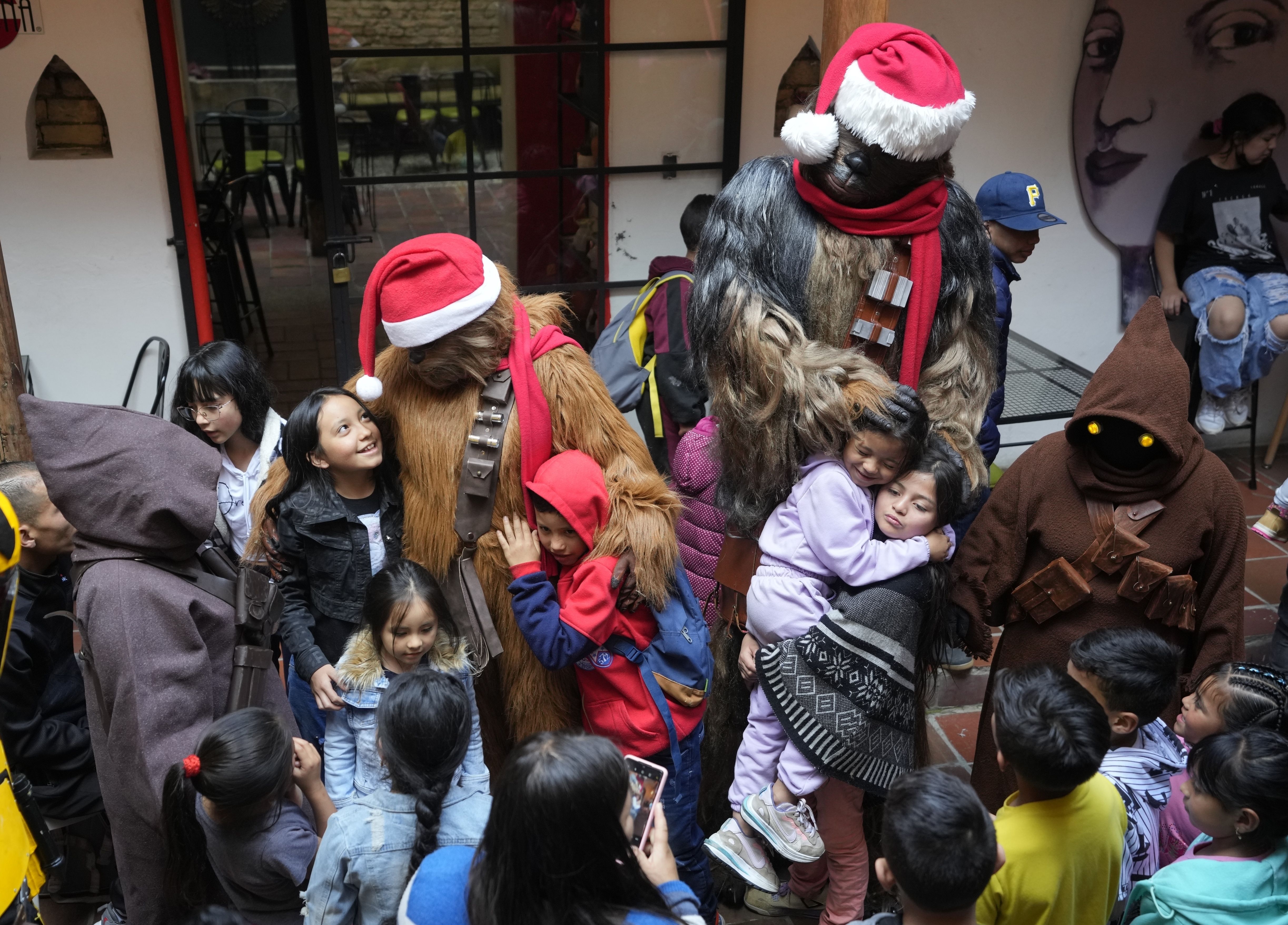 Voluntarios disfrazados de personajes de Star Wars abrazan a niños antes de la entrega de regalos en un evento solidario organizado por la fundación "Vida Nueva" que trabaja para ayudar a extrabajadoras sexuales y víctimas de violencia, en Bogotá, Colombia, el jueves 22 de diciembre de 2022. (AP Foto/Fernando Vergara)