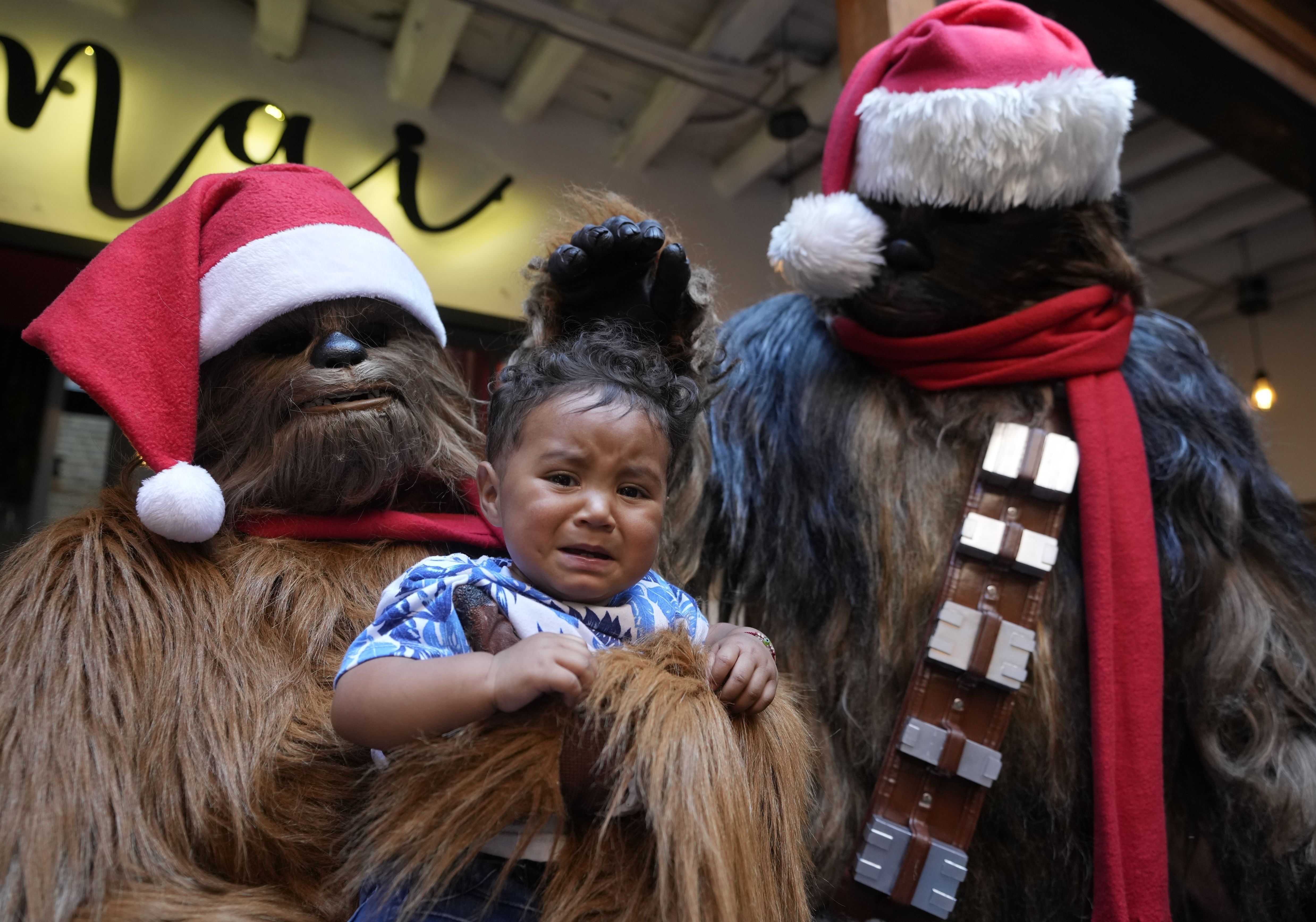 Un voluntario disfrazado del personaje de Chewbacca en Star Wars sostiene a un niño para la foto antes de entregar regalos en un evento solidario organizado por la fundación "Vida Nueva" que trabaja para ayudar a extrabajadoras sexuales y víctimas de violencia, en Bogotá, Colombia, el jueves 22 de diciembre de 2022. (AP Foto/Fernando Vergara)