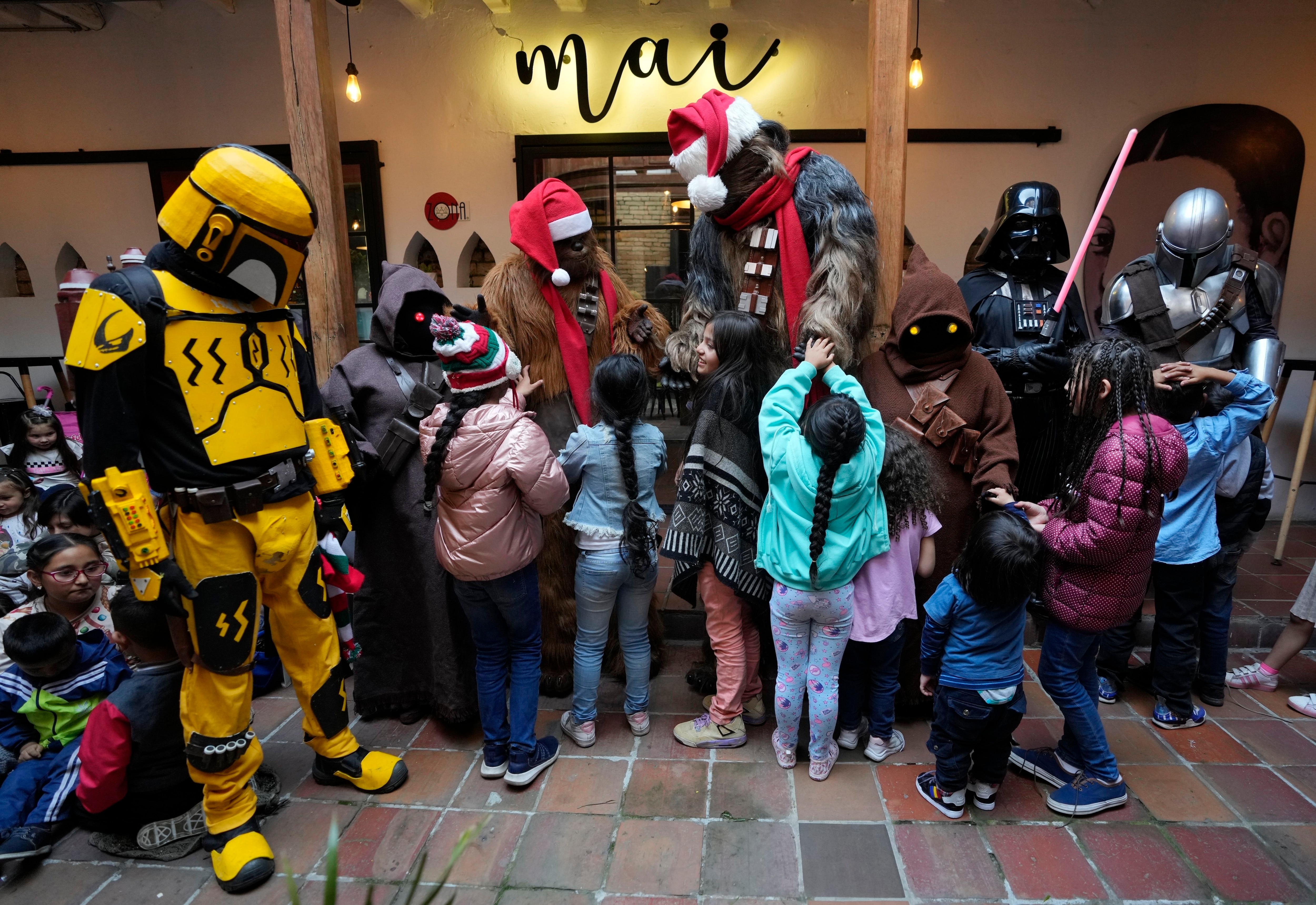 Voluntarios disfrazados de personajes de Star Wars agasajan a los niños que llegan para recoger regalos en un evento solidario de la fundación "Nueva Vida" que trabaja para ayudar a extrabajadoras sexuales y víctimas de violencia, en Bogotá, Colombia, el jueves 22 de diciembre de 2022. (AP Foto/Fernando Vergara)