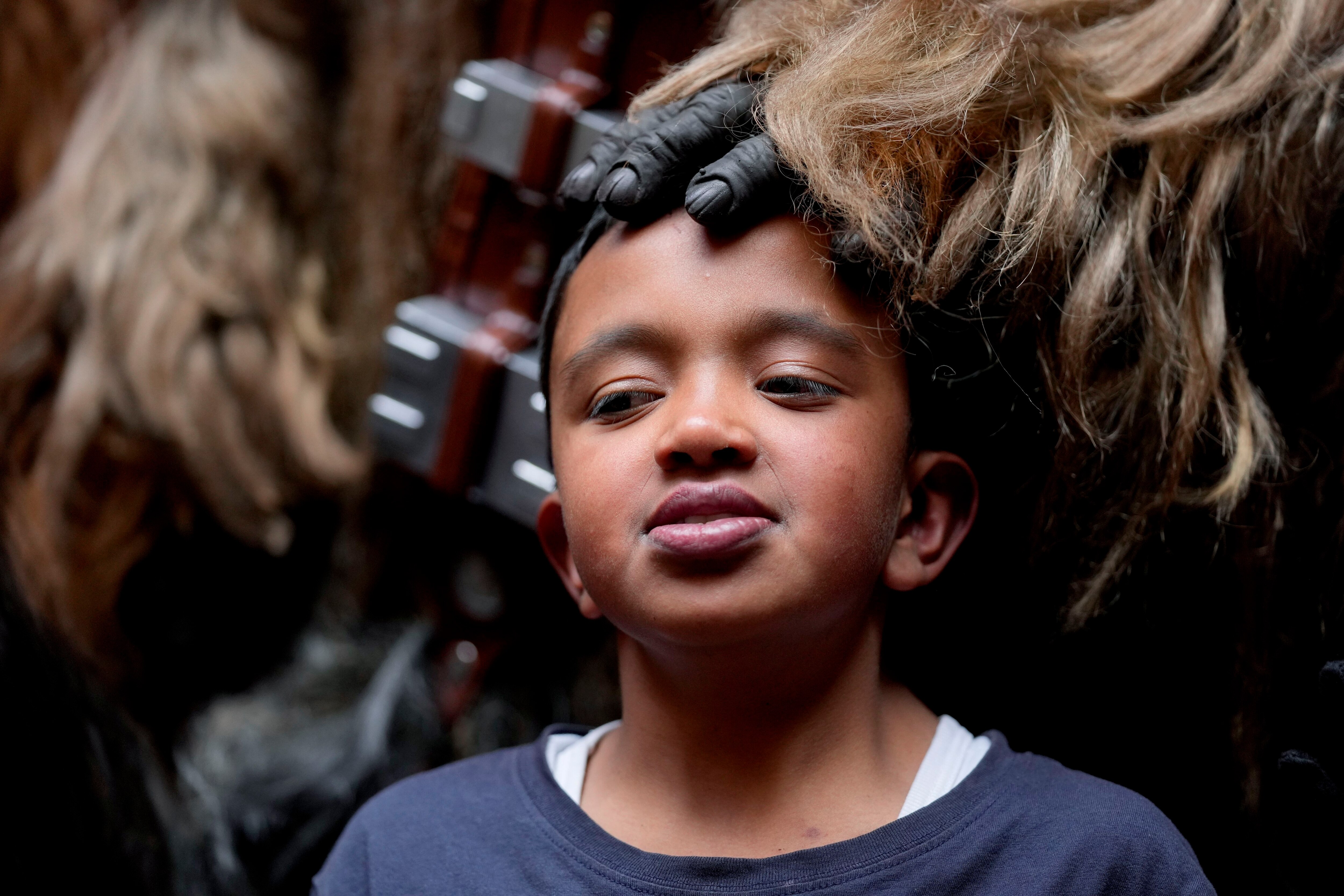 Un niño posa para la foto con un voluntario disfrazado de uno guerrero wookie de Star Wars en un evento solidario organizado por la fundación "Vida Nueva" que trabaja para ayudar a extrabajadoras sexuales y víctimas de violencia, en Bogotá, Colombia, el jueves 22 de diciembre de 2022. (AP Foto/Fernando Vergara)